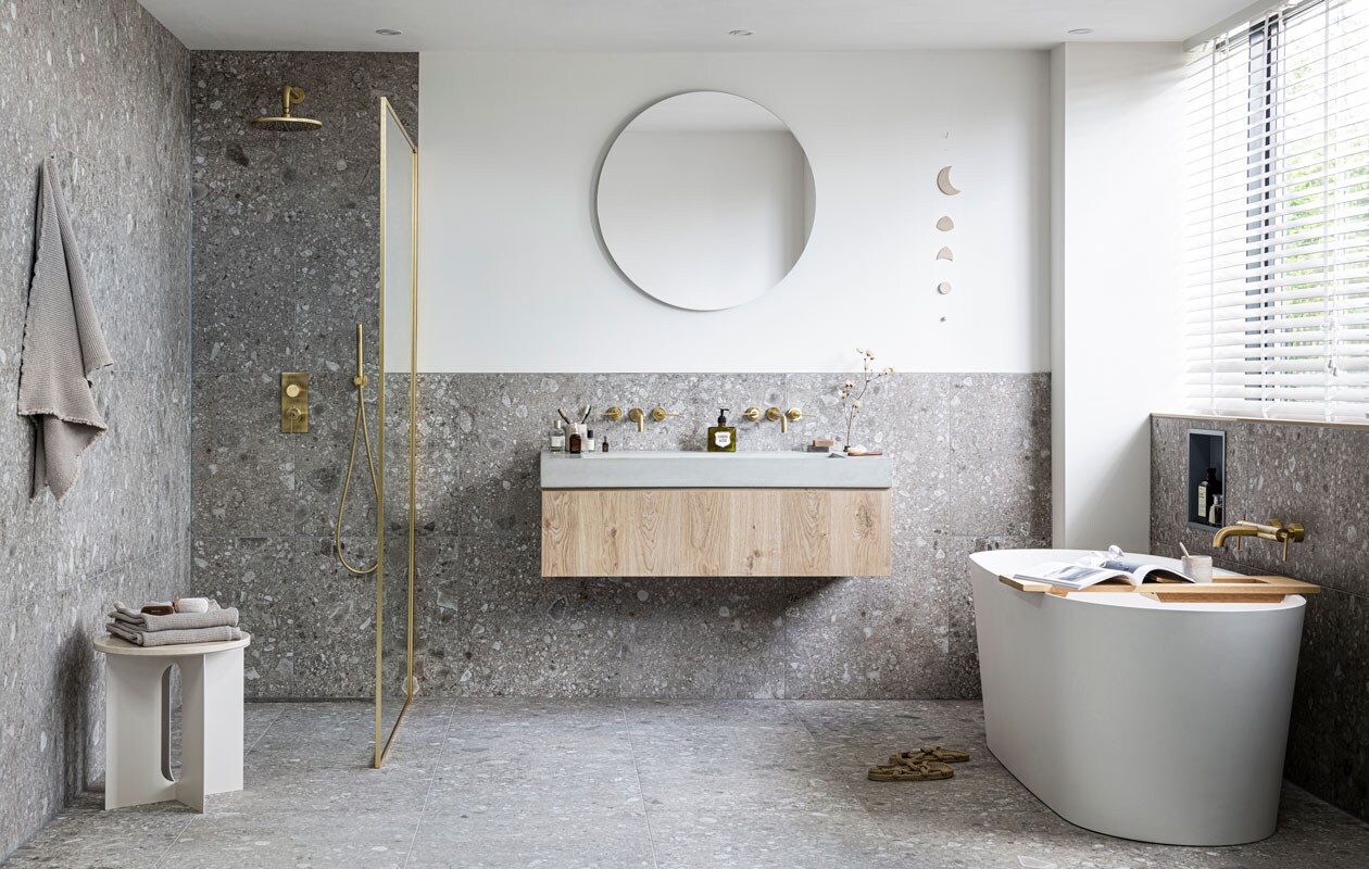 Vrijstaand bad Tub in kleur Powder White, 165x72x60 cm (lxbxh) € 3085,-, badplank Board in blank eiken, 78x27 cm (lxb) € 275,-, badthermostaat Grip met hendels in kleur Bronze € 895,- (ook in kleuren Black Steel, Brushed, Charcoal en Chrome). Wastafel onderkast Cube van eikenfineer in kleur Oak, met 1 lade, 30x120x43,5 cm (hxbxd) € 519,- (ook in kleuren Oak Black en in 30x60x43,5 cm € 455,- en 30x90x43,5 cm € 469,-), wasbak Tank van beton in kleur Concrete, zonder kraangaten,10x120x46 cm (hxbxd) € 1199,- (ook in kleuren Concrete Black en White en diverse formaten), wandkraan Grip afdekset 2-greeps, uitloop 23 cm in kleur Bronze € 453,- (ook in kleuren Black Steel, Brushed, Charcoal en Chrome). Douchethermostaat Grip met hendel in kleur Bronze € 839,- (ook in kleuren Black Steel, Brushed, Charcoal en Chrome), hoofddouche Solid in kleur Bronze, 25 cm € 570,- (ook in kleuren Black Steel, Brushed, Charcoal en Chrome), douchearm Solid 30 cm in kleur Bronze € 144,- (ook in Black Steel, Brushed, Charcoal en Chrome), staafhanddouche Solid in kleur Bronze € 92,- (ook in Black Steel, Brushed, Charcoal en Chrome) met doucheslang in kleur Bronze € 48,- (ook in Black Steel, Brushed, Charcoal en Chrome), slangaansluitknie Solid in kleur Bronze € 76,- (ook in Black Steel, Brushed, Charcoal en Chrome) , tegels Composite Dark Grey, 60x60 cm per m² € 57,50 (ook in 120x120, 30x60, 15x60 cm, Muretto en Mozaïek in 30x30 cm).M.m.v. menuspace.com (bijzettafel), hm.com (handdoeken), ohmyhome.nl (muurhanger), stories.com (slippers, bril), restored.nl (mok), annemiekebootsceramics.nl (lepel), sostrenegrene.com (goudkleurige ophangknop), tegeldepot.nl (douchescherm, ronde spiegel, opbergnis), maisonnl.com (houten nagelborstel). Overig privébezit. vtwonen 08-2020| fotografie Sjoerd Eickmans | styling Kim van Rossenberg