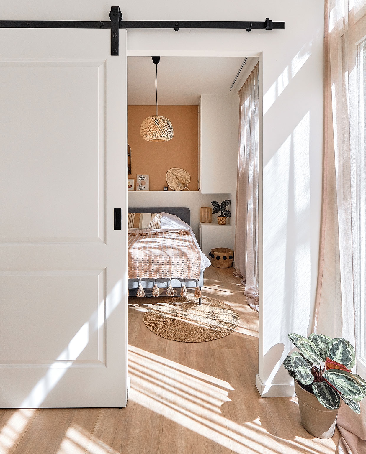 Schuifdeur op maat gemaakt. Gordijnen whkmp’sown Wehkamp. Rond vloerkleed Xenos. Bed Ikea. Sprei en kussen Maisons du Monde. Hanglamp Jysk. Muurverf in kleur Piramide van Praxis. Lijstjes gemaakt door een vriendin. Waaier Maisons du Monde. Plantenpot Ikea. Rieten nachtlampje Maisons du Monde. Mand met pompoms H&amp;M Home. Plantenpot vooraan herkomst onbekend. NEE | vtwonen special tiny houses | Fotografie Roos Oosterbroek dRaw studio 24  | Tekst Sara Madou
