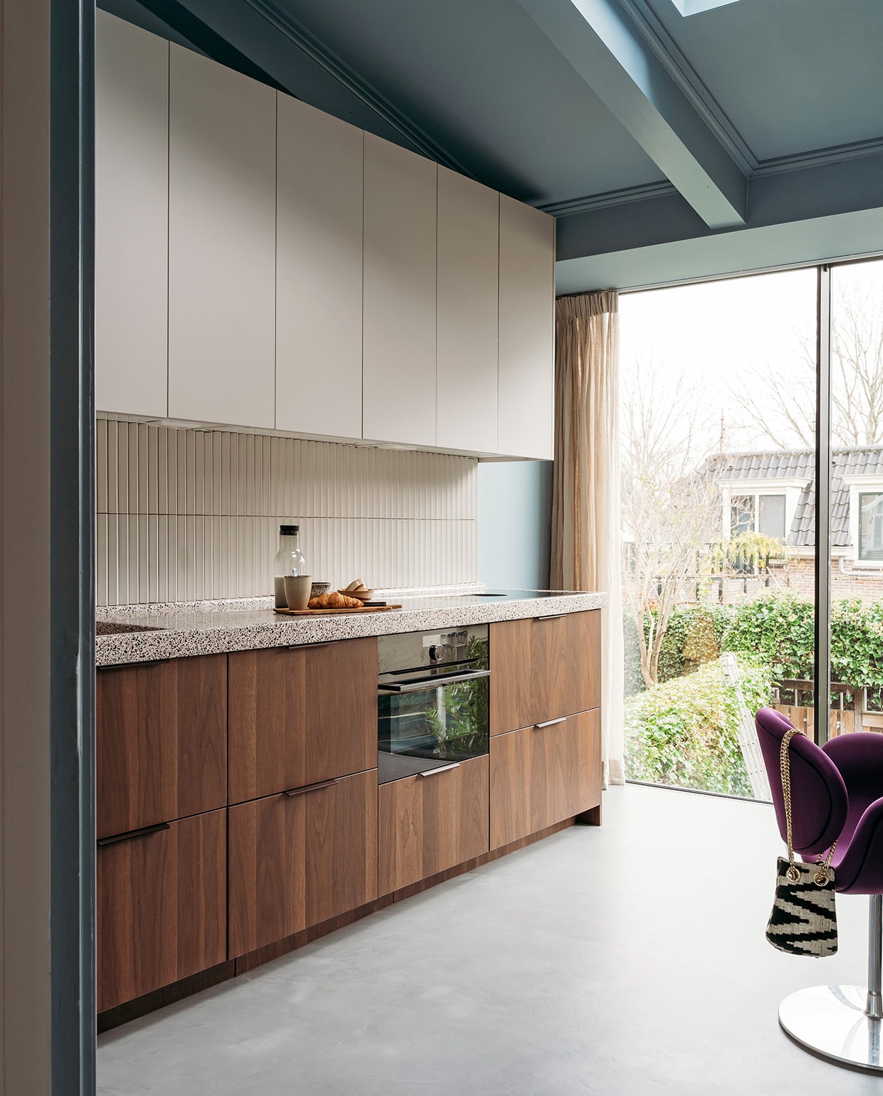 Basis keuken Ikea, fronten in kleur Smoked Walnut (onder) en Kasjmiergrijs via Frontz, terrazzo blad Rosa Bian Terrazzowerken. Wandtegel Rombini triangle small white van Mutina. Plank Action, mokken Xenos, karaf Hema. Verf muur en plafond R0.10.60 van Sikkens. Stoelen Little Tulip van Artifort via Marktplaats. Tas Rough Studios. Vloer Cem-Line Micro van Loos Betonvloeren. vtwonen 03-2021 | productie Coco Features | styling Laurien Deken | fotografie Inge Korver