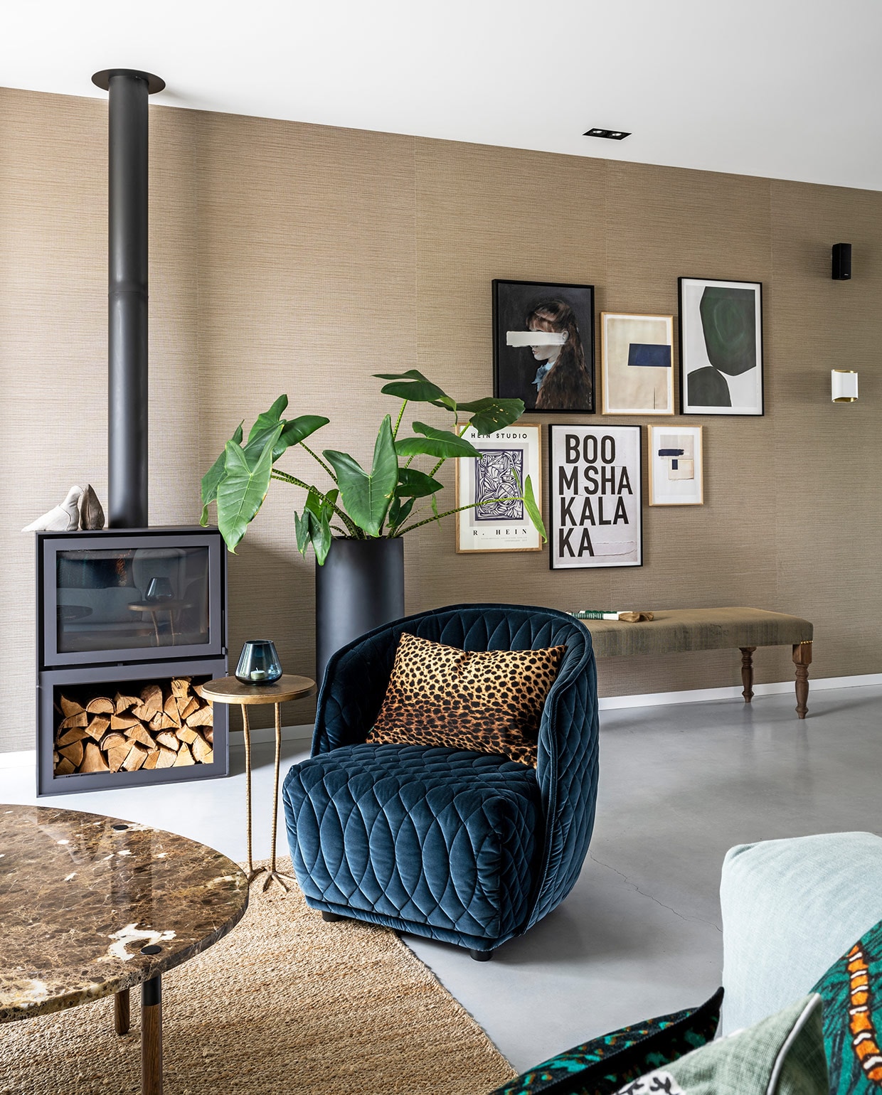Behang Aztec Arte, houtkachel Barbas, zwarte plantenpot Micha Hulshof Bloembinder, bank La Vie Bohème met stof van Jim Thompson, fauteuil Redondo Moroso, panterkussen Mes, salontafel Bolia, bijzettafel Birdy Side Table Urban Outfitters, blauwe waxinelichthouder Prospectt, kunstwerken aan de muur van My Deer Art Shop en The Poster Club. vtwonen 03-2021 | Productie CocoFeatures | Styling Wendy Verhaegh | Fotografie Stan Koolen