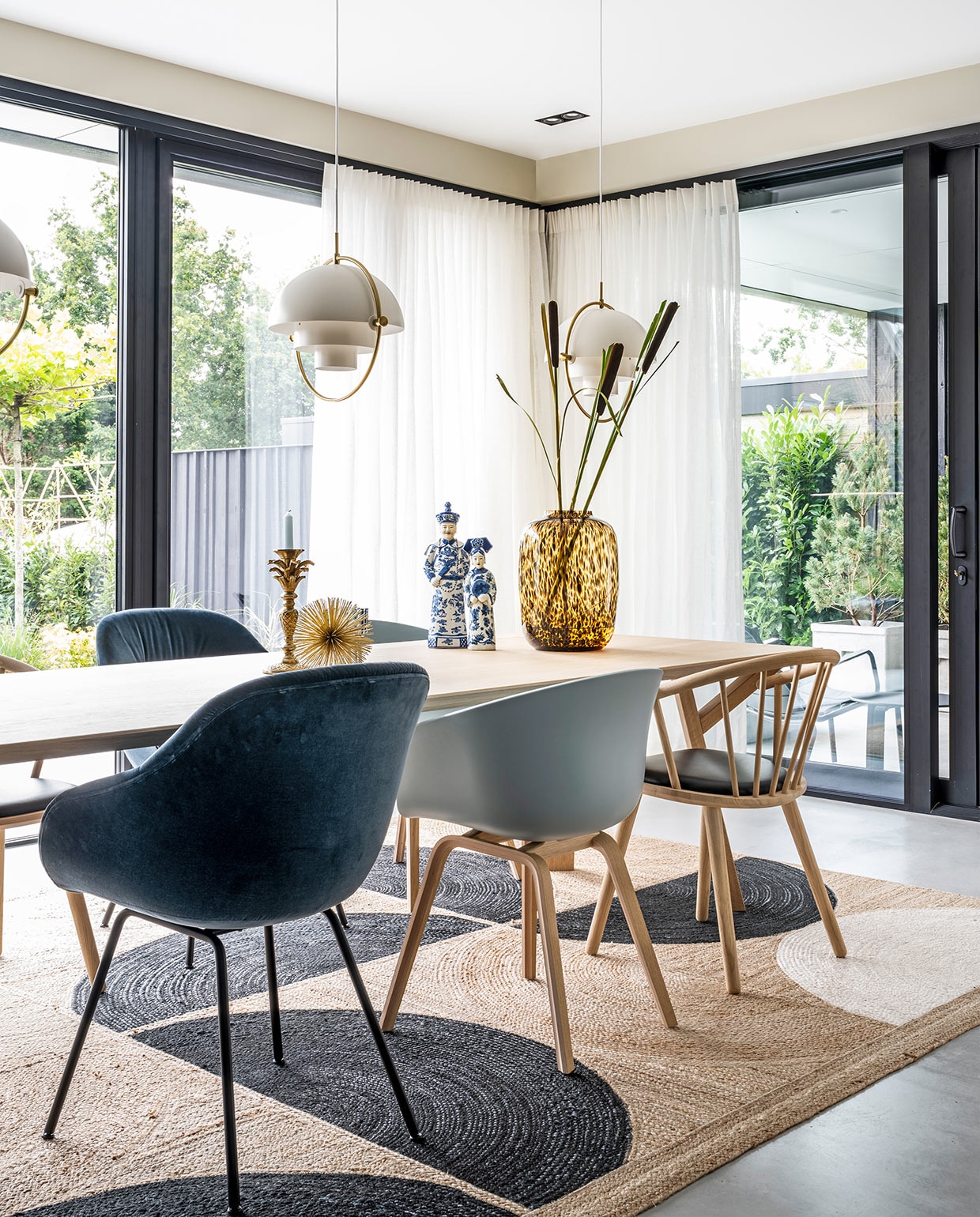 Hanglampen Multi-Lite Gubi, tafel Arp Design, vloerkleed litis, donkerblauwe en lichtblauwe stoelen Hay, houten stoelen zwarte zitting Bolia, gouden stekelitem Loods 5, kandelaar palmboom Anna+Nina, beelden Asian Mix Interior, vaas Artic Cheetah Vase the World, linnen gordijnen Interstil. vtwonen 03-2021 | productie CocoFeatures | styling Wendy Verhaegh | fotografie Stan Koolen