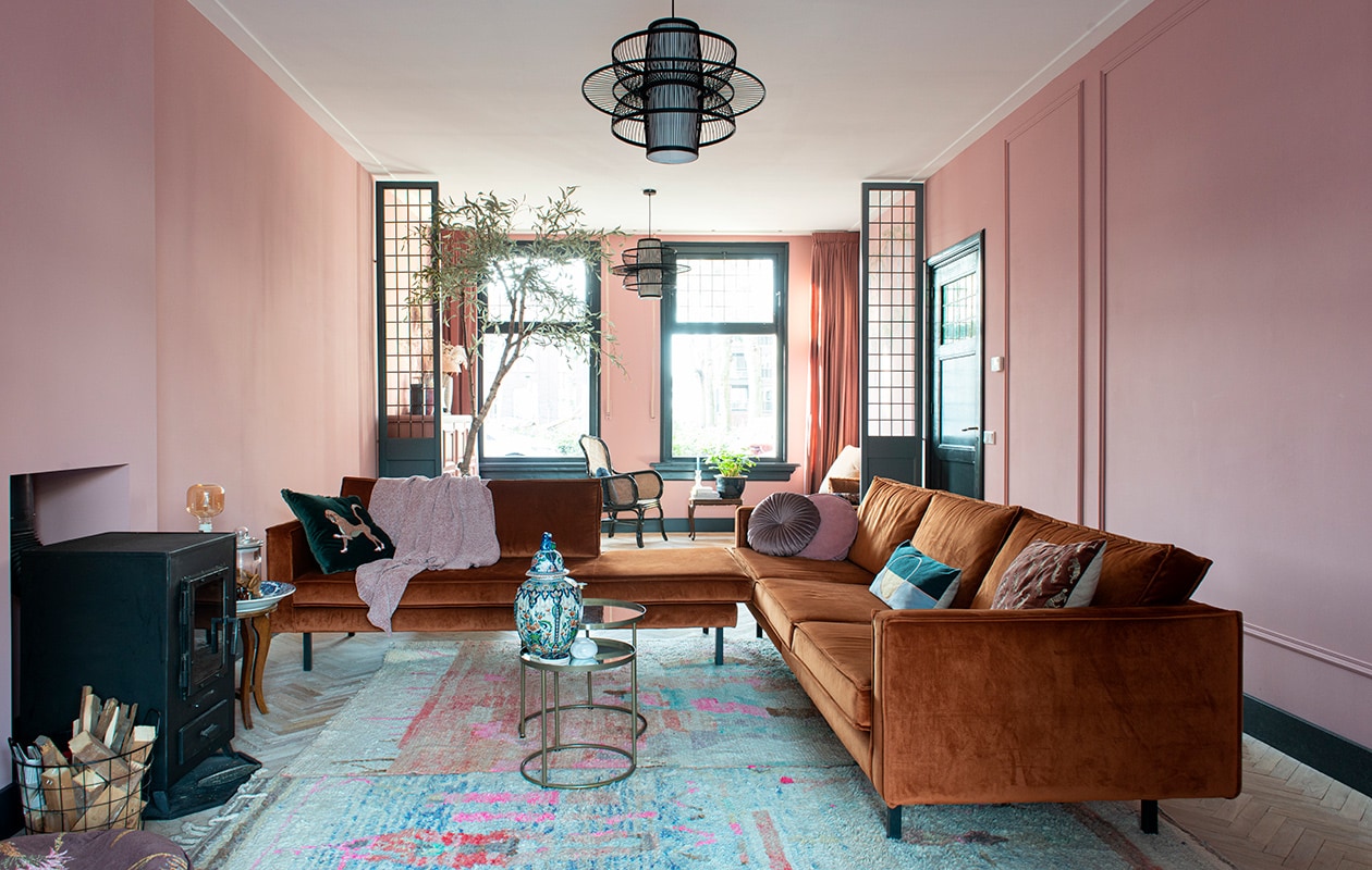 Muurverf Hellebore 275 van Little Greene. Banken BePureHome. Kussen met print Sissy-Boy. Velvet kussen Jysk, roze kussen Kwantum, plaid H&amp;M Home. Vloerkleden gekocht in Marrakech. Bijzettafel en Delfts blauwe schaal familiestukken. Glazen pot en vaas met deksel gekregen. Tafels en gouden waxinelichthouder Action, onderzetters gekocht op Rhodos. Waxinelichthouder kringloopwinkel. vtwonen 03-2021 | fotografie Caroline Coehorst