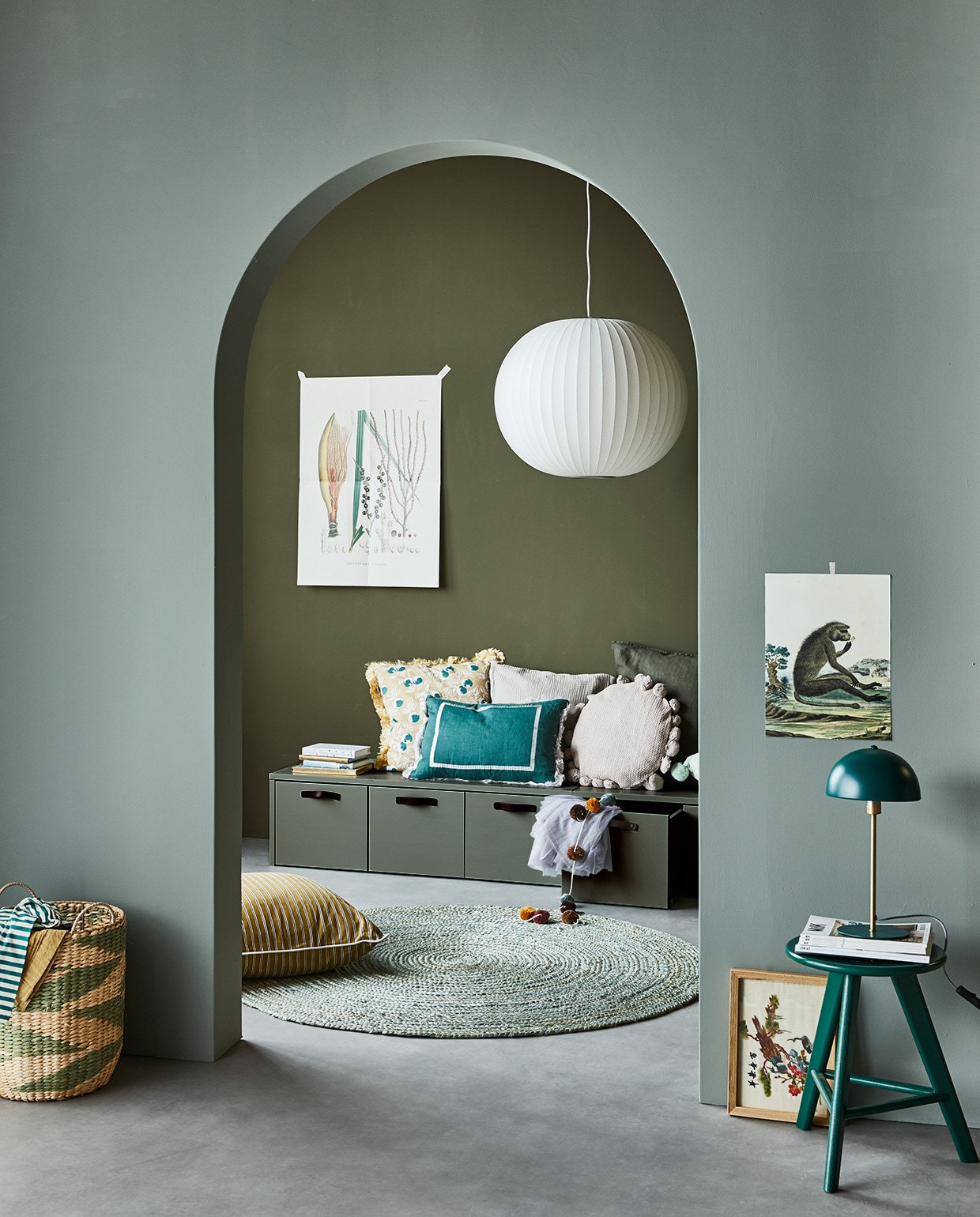 Muurverf op achterste wand Camouflage, op boog Soap. Grenenhouten kistbank Stage in kleur Soap van vtwonen, lamp van Hay, vloerkleed van Kave Home, mand en kussen met kwastjes van Bloomingville, staande lamp van Leitmotiv), palais.com (oker kussen met strepen, zeegroen kussen, geel gedessineerd kussen), neeflouis.nl (kruk), zarahome.nl (groen kussen, ecru kussen), hm.com (slinger, kussen met pompons), flo4kidz.nl (kleding). Overig privébezit. vtwonen 04-2021 | Styling Cleo Scheulderman | Fotografie Jeroen van der Spek