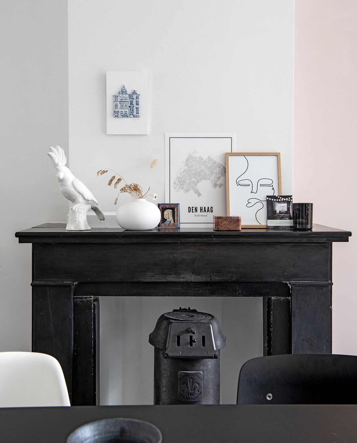 Open haard en gietijzeren kachel zaten al in het huis. Kaketoe Pols Potten. Vaas Urban Nature Culture. Print huizen Alexandra Breeze Ceramics, kaart van Wijck, print gezichten Studio Lisa. Antieke houten doosje vintage, foto van een schilderij dat Britts tante van haar maakte. vtwonen 02-2021 | Productie Insidehomepage | Styling Esther Jostmeijer | Fotografie Louis Lemaire