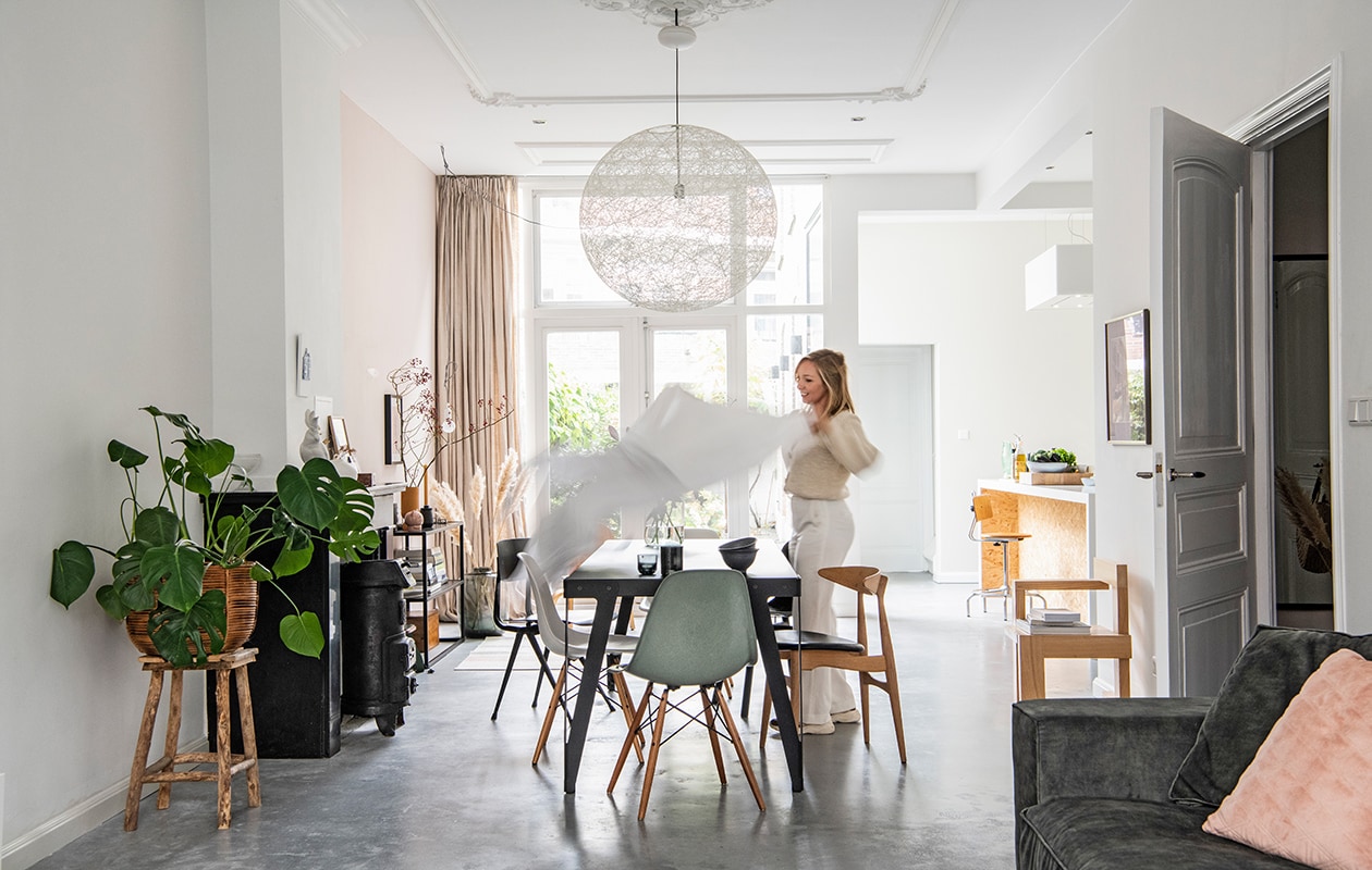 Muurverf links ral 9016, rechts E0.05.75 van . Tafel Lloyd en donkere houten stoel Wendela van Functionals, groene stoel DWS Eames van Vitra, zwarte stoel Revolt van Friso Kramer, houten stoel met zwarte zitting CH33 van Hans Wegner. Theepot Bredemeijer, mok en zwarte schaal Loods 5, vaas Bloomon. Hanglamp Random Light van Moooi. Houten stoel rechts gemaakt door Sanders vader, naar ontwerp van Gerrit Rietveld. Schilderij rechts Titus Meeuws. Keukeneiland Houtwerk, barkruk vintage, herkomst kraan onbekend, afzuigkap Zen van Novy. Bank Noelle van Room 108, kussen van HKliving. Planten-mand en kruk van tuincentrum. vtwonen 02-2021 | Productie Insidehomepage | Styling Esther Jostmeijer | Fotografie Louis Lemaire