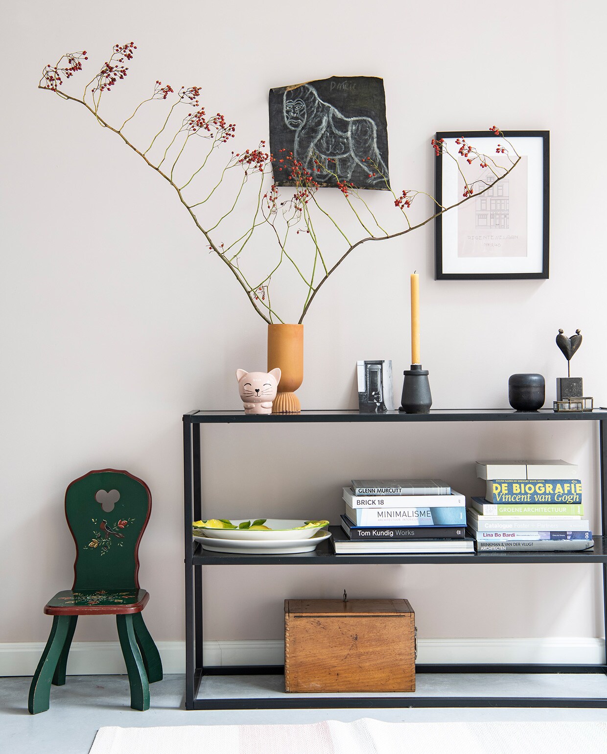 Groene kinderstoel erfstuk, sidetable Karwei. Houten kist en glazen doosje vintage, vloerkleed Hay, vaas HKliving, roze kat Hema, herkomst zwarte kandelaar onbekend, schalen souvenir uit Italië, beeld van Monique Bruls. Schets aap souvenir uit Oeganda, print huis gemaakt door Britt. Muurverf E0.05.75 van Flexa. vtwonen 02-2021 | Productie Insidehomepage | Styling Esther Jostmeijer | Fotografie Louis Lemaire
