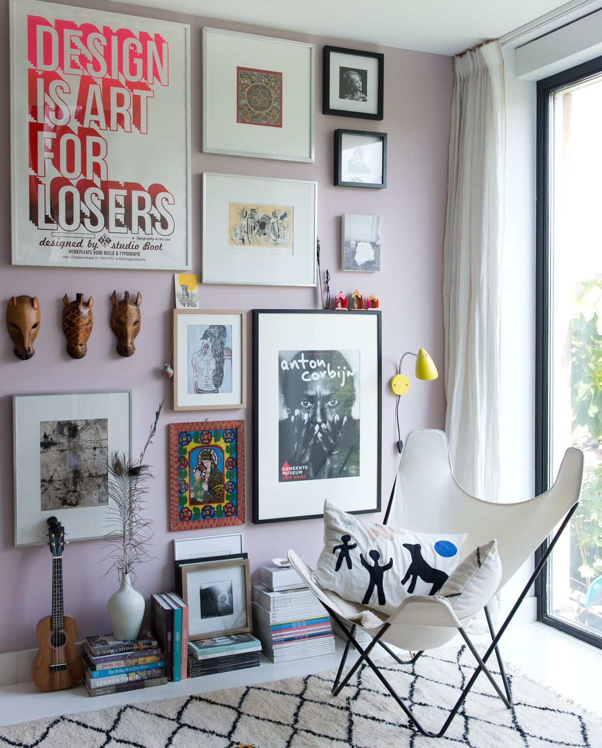 Kunst, posters en prints van o.a. Studio Boot, Ivonne van der Velden, Anton Corbijn, Frank Willems en Mark Rothko. Witte lamp Tolomeo van Artemide. Chesterfieldbank marktplaats.nl. Vintage Jieldé lamp. Geel muurlampje Waterquest. Kleed uit Marokko. Kussens van stof uit Tanzania. Vlinderstoel erfstuk. Kussen Neeltje Geurtsen. Houtkachel Bullerjan. Roze verf Noa van Fairf. vtwonen 12 binnenkijken special 2019 | Styling Jet van der Graaf | Fotografie Trui Heinhuis | Tekst Caroline Westdijk