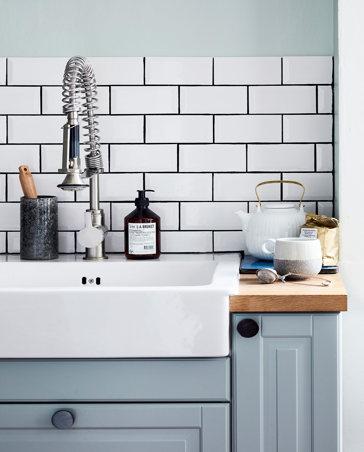 Muurverf 7555 Soft Mint van Jotun, verf kasten 7163 Minty Breeze van Jotun. Keuken was al aanwezig, Hammershøi theepot Kähler, overige keukenaccessoires Ikea, Tchibo en Georg Jensen Damask. Tegels Fired Earth en Arttiles. vtwonen 02-2021 | Productie en fotografie Stine Christiansen | Styling Gitte Christensen