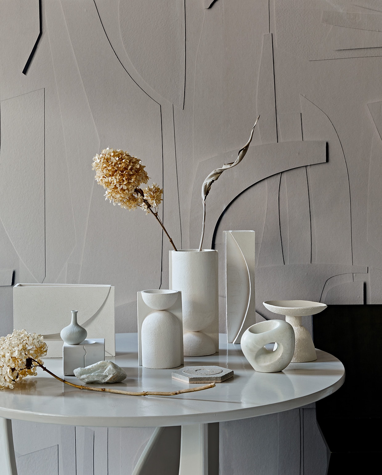 De serie vazen The Sand van witte chamotte klei kwam tot stand door een samenwerking van drie creatieven van Art in Return, Studio Yen en By Joa Amsterdam. Links smalle vaas Sun € 125,-, in het midden ronde vazen The Sand per 2 € 330,-, rechts rechthoekige vaas Moon € 230,- (, artinreturn.nl, byjoa.nl). Rechtsvoor sculptuur van speksteen € 350,- (lisetteleegwater.nl). Schaal keramiek op voet Moon Totem van Marlies Huybs € 300,- (studio-yen.com). Kleine porseleinen vaas € 21,95 (). Ronde tafel 120×75 cm (Øxh) vanaf € 750,- (com-anders.nl). Behang White Spirit, prijs op aanvraag, wordt op maat geprint (pascale-risbourg.com). Gedroogde hortensia’s en strelitzia (edenique.nl). Gietvorm in gips, stuk speksteen links vooraan (keramikos.nl). vtwonen 02-2021 | Styling Cleo Scheulderman | Fotografie Jeroen van der Spek
