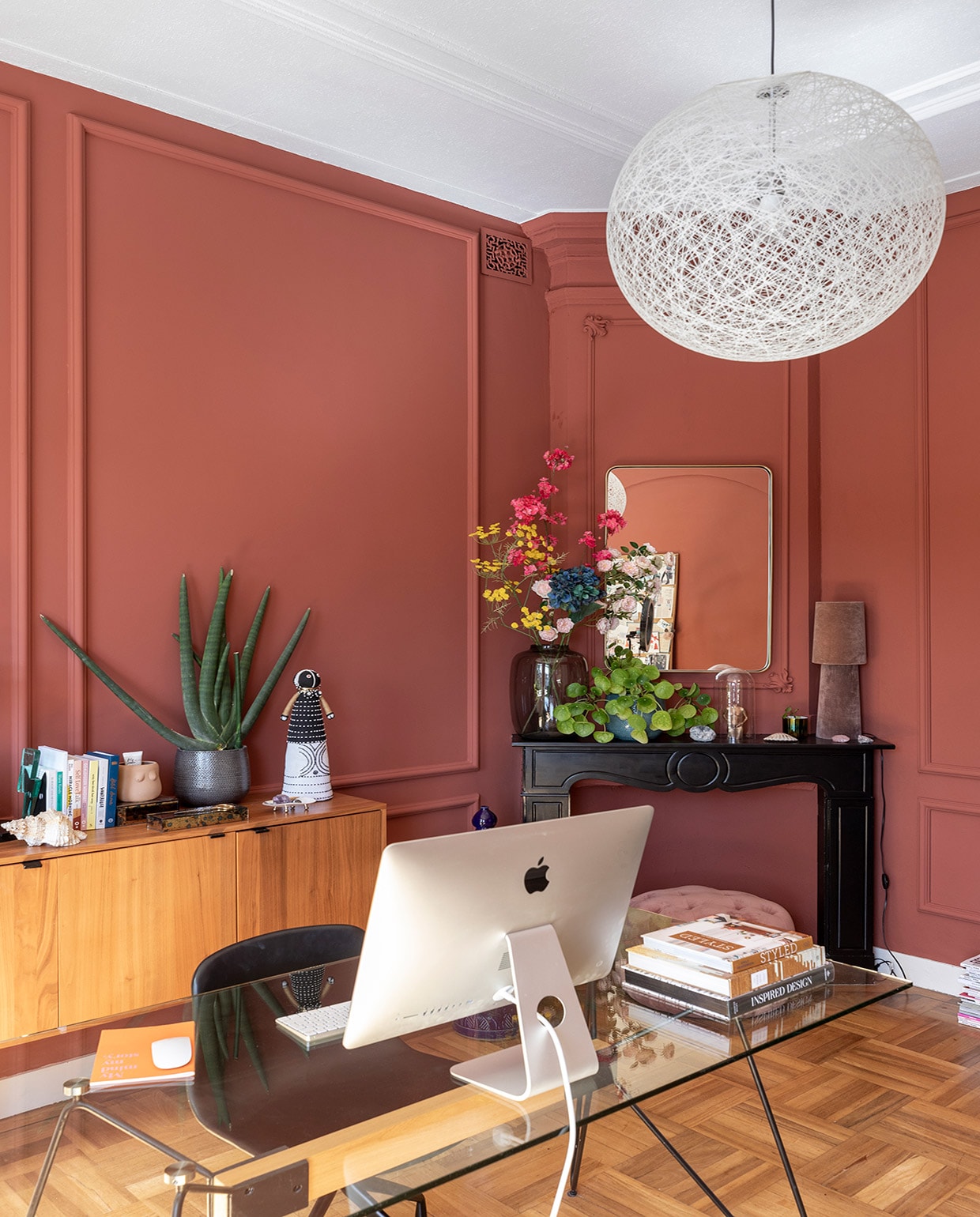 Muurverf Picture Gallery Red van Farrow &amp; Ball, originele vloer uit 1889, hanglamp Moooi, dressoir Karwei, bureau Made, zwarte stoel Hay, blauwe vaas uit Bali, spiegel Westwing. Op het dressoir: tweekleurenlamp kap kringloop, , voet Yaya. Kleine vaas Des Pots. Goud-zwarte lamp H&amp;M Home. Blauwe vaas en kunstbloemen Jasmijn Bloembinders. Klein voorwerp voor blauwe vaas Jaspis steen. Op de schouw: roze lamp kap kringloop, voet Yaya. Citroenboom en pot ’s Zomers Bloemen. vtwonen 01-2021 | Productie en Fotografie Margriet Hoekstra | Tekst Anna van der Heijden