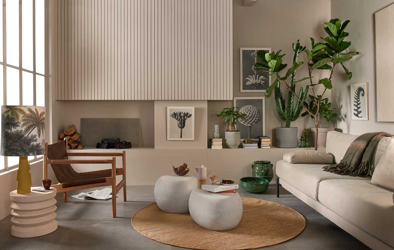 3-zitsbank Sleeve in linnen/katoen, 242x94x83 cm (lxbxh), inclusief 2 kussens € 1599,-, fauteuil Chill € 399,- (basiclabel.nl). Oker vloerkleed van Linie Design, 170 cm (Ø) € 224,25, bijzettafel Pebble van vtwonen, per stuk vanaf € 129,-, grijze bloempot links van d&amp;m € 13,80 (vtwonen.nl). Koffiepot € 64,90, mokken per 4 € 34,95, bruine kom per 4 € 34,95, ecru stenen bijzettafel € 129,-, keramische lampenvoet € 110,-, lampenkap Jungle € 74,95, retro vaas op boeken € 29,95 (hkliving.nl). Groene plantenpot € 169,-, schaal € 59,95, kandelaars vanaf € 21,- (householdhardware.nl). Artwork van Karl Blossfeldt (basiclabel.nl). Planten, grote hoge vooraan: Ficus Lyrata, erachter v.l.n.r. Ficus Benghalensis, Euphorbia Erytrea in grijze pot en Ficus Microcarpa (plantenverhuur.nl). Taupe plantenpot via goed gesorteerde bloemenhandel.