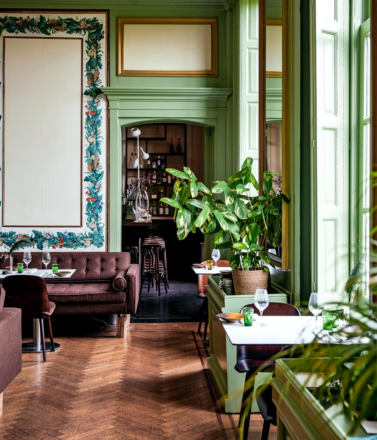 Het restaurant heeft de authentieke kleur groen, met op de wanden handgeschilderde guirlandes en plafonds vol ornamenten. vtwonen 01-2021 | productie Roos Stalpers &amp; Fee van ’t Veen | fotografie Ernie Enkelaar