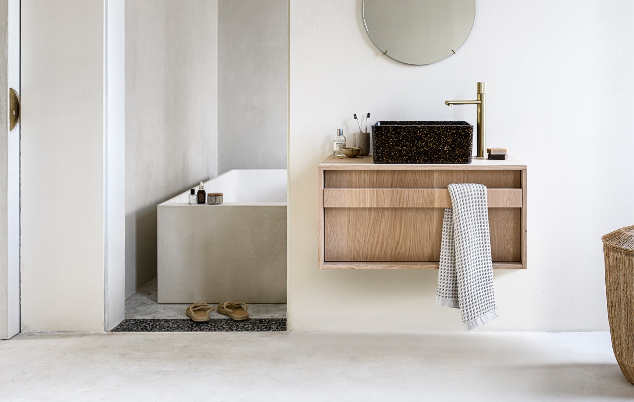 Kleur op de muur Mikonos van We Are Wow Makers, prijs op aanvraag (anoukb.com). Messing spiegel van Moebe, 50 cm (Ø) € 175,-, wastafel van houtcomposiet bestaande uit echte houtsnippers WB07 in kleur Root € 719,95 (aedamanthony.nl). Hoge wastafelkraan van geborsteld messing € 199,- (tworooms.nl). Bad ontwerp van Anouk B in samenwerking met Not Only White, prijs op aanvraag (anoukb.com). Zeep € 10,95 (zeeplokaal.nl). Handdoek Mova van Marc O’Polo 50×100 cm € 14,95, schaaltje Juras € 5,90 (vtwonen.nl). Parfum van Le Labo, vanaf € 105,- (skins.nl). Tandenborstelbeker € 7,99 (hm.com/nl). Tandenborstels van Meraki € 6,95 (Loods5.nl). Slippers € 29,95 (zarahome.com). Overig privébezit. vtwonen 01-2021 | Styling Kim van Rossenverg | Uitvoering Richard van Meerveld | Fotografie Sjoerd Eickmans