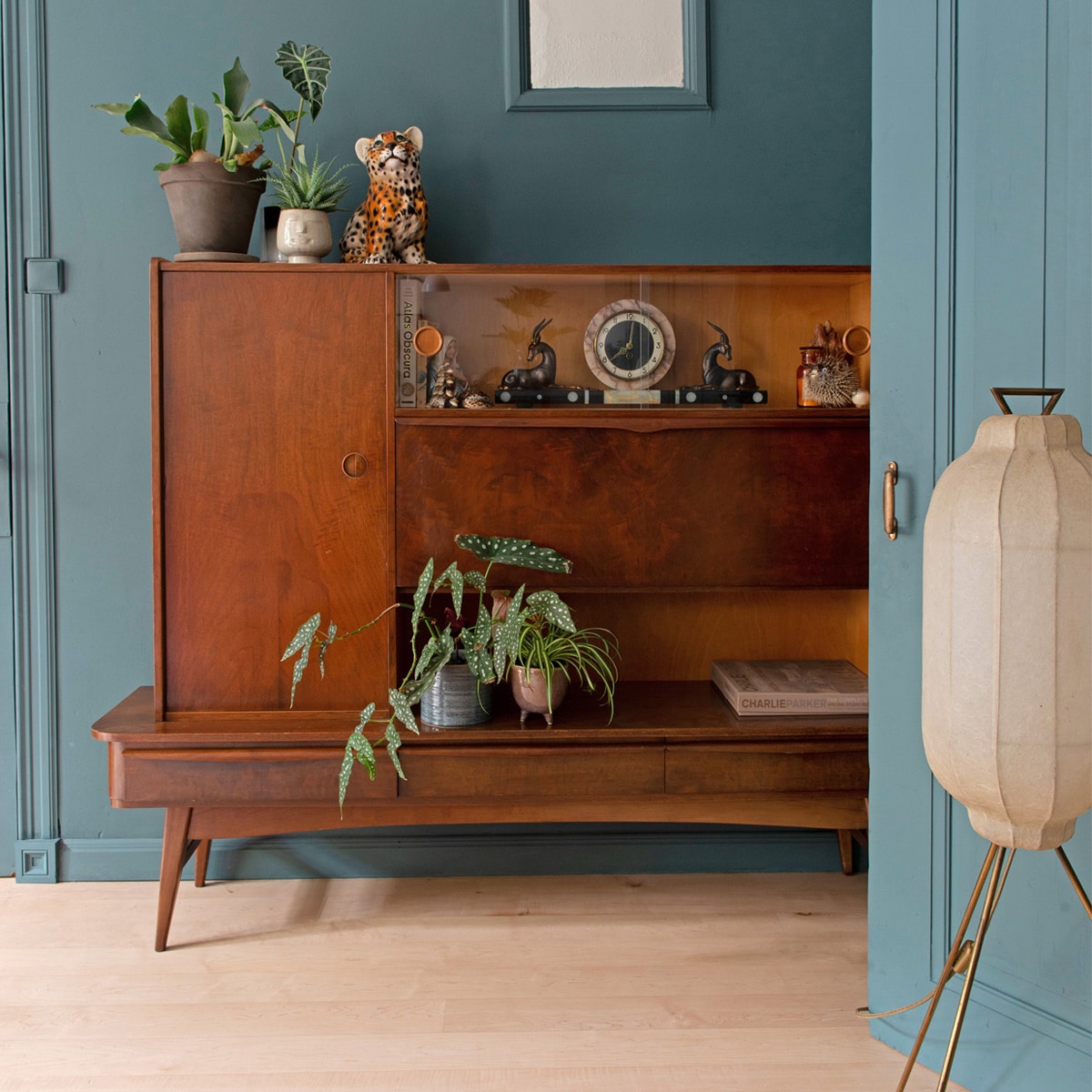 Muur- en lakverf Inchyra Blue van Farrow&amp; Ball. Buffetkast en accessoires erin vintagevondsten. Beeld tijger Verkoopfabriek Assen.Driepootlamp StrangeAvenue. Plantenpottenkringloop, planten Alocasia, hertshoorn envetplant en Stippenbegonia. Achter hetoriginele bedsteeraam in de muur is de hal. vtwonen 01-2021 | styling Jeske Weel | fotografie Caroline Coehorst