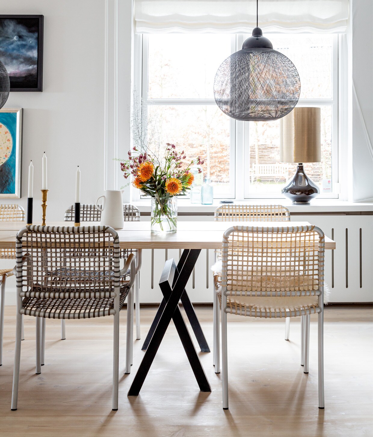 Muurverf Strong White van Farrow &amp; Ball. Tafel en zwart servies zelfgemaakt. Stoelen Casa Shop. Kan Louisiana Museum of Modern Art. Kandelaars erfstuk. Hanglamp Moooi. Tafellamp Rue Verte. Schilderij Kurt Trampedach.