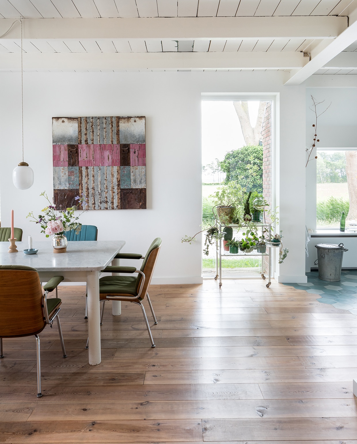 Tafel, vintage Giroflex-stoelen, vintage Siematic-keuken en Kandem-muurlampen Marktplaats. Aardewerken kandelaar rommelmarkt. Hanglamp, houten kandelaar en vaasje uit de winkel van Rixt en Clara, de Sip &amp; Clara Pop-up Store. Antieke radiator van pop-up store in Groningen. Portugese vloertegels Mosaic del Sur. Groen glaswerk rommelmarkt, pan Nicolas Vahé, bakelieten schakelaars Frummes.nl. Kunstwerk Henk Kastelijn, tegel zeepaardje op afzuigkap rommelmarkt. De ijsblauw geschilderde hoge deur is hergebruikt. vtwonen DIY special 01-2020 | styling Sabine Burkunk | fotografie Hans Mossel