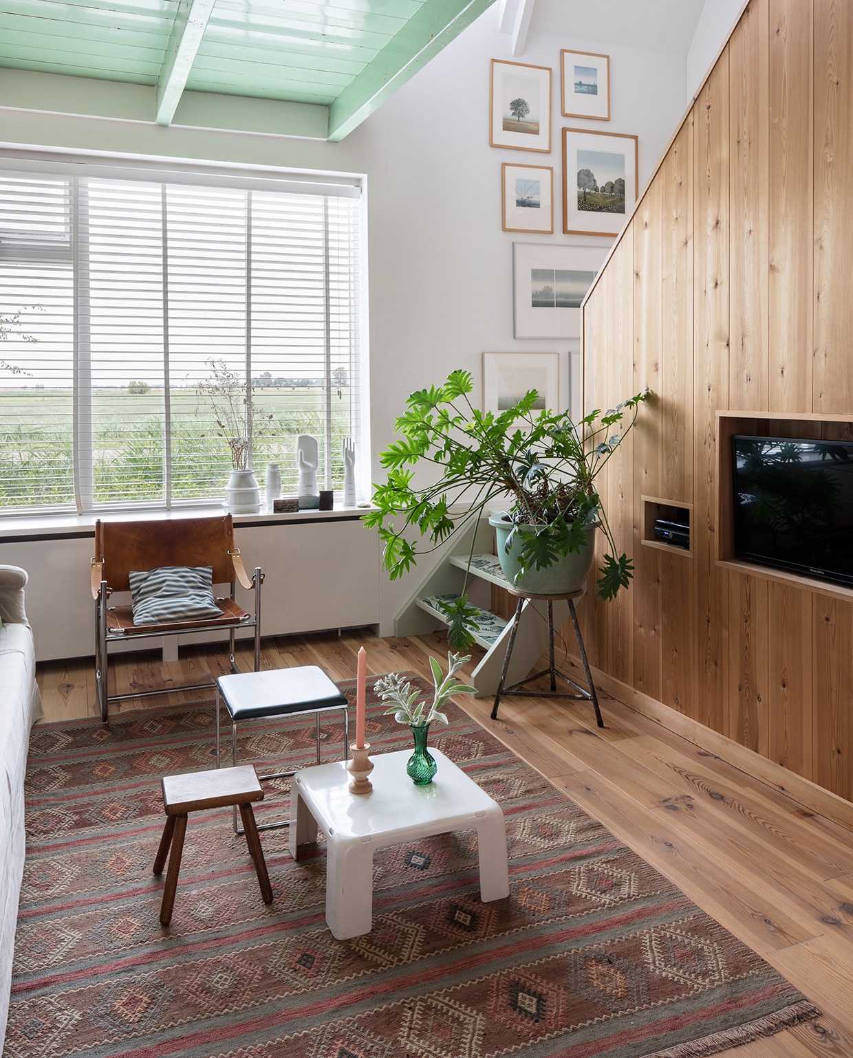 Grenen planken voor huisje Wytske’s Houthandel. Erop twee roerklikken van houten schepen uit Stavoren. Tafel, vintage Giroflex stoelen en vintage Giroflex bureaustoel Marktplaats. Hanglampen, kandelaars en vaas Sip &amp; Clara Pop-up Store. Collectie Hollandse kleurenlitho’s Henk Kastelijn. Grenen vloer Eerlijk Hout. vtwonen DIY special 01-2020 | styling Sabine Burkunk | fotografie Hans Mossel