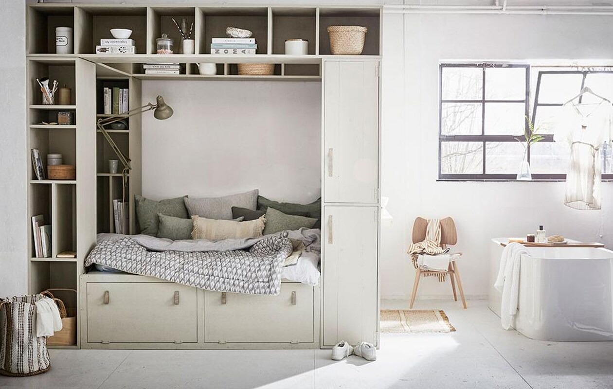 Grote kast en bedombouw zijn op maat gemaakt (Combitex). De kast is geschilderd in de kleur Bone van Farrow &amp; Ball (De Ru). Linnen kussen Jade Green van By Mölle, linnen kussen Jade Moss Green van By Mölle, linnen kussen Jade Green van By Mölle (vtwonen.nl). Linnen kussens groen en grijs, witte porseleinen potten met deksel en etiket, houten ronde doos (De Weldaad). Vloerkleed, wit met zandkleurige mand, ecru kussen (Madam Stoltz). Gevoerde Ikat sprei, katoenen Ikat kaftan, marmeren zeepbakje op badplank, marmeren beker in kast (Nordal). Stoel Butterfly van Ercol (De Machinekamer). Ochtendjas gestreept, witte wafeldoek, grijze handdoek (Zara Home). Vrijstaand bad Nijl, badplank (Ton Scholten). Badborstel, Loofah spons (Dille &amp; Kamille). Linnen dekbedovertrek in Misty grey, kussensloop Misty Grey (By Mölle). Witte beker, wit kommetje in kast, kan (Kitchen Trend Products). Ronde doos met goudkleurig deksel, rieten mandjes in kast (H&amp;M Home). Tadelakt zandkleurig potje met deksel (Maison NL).