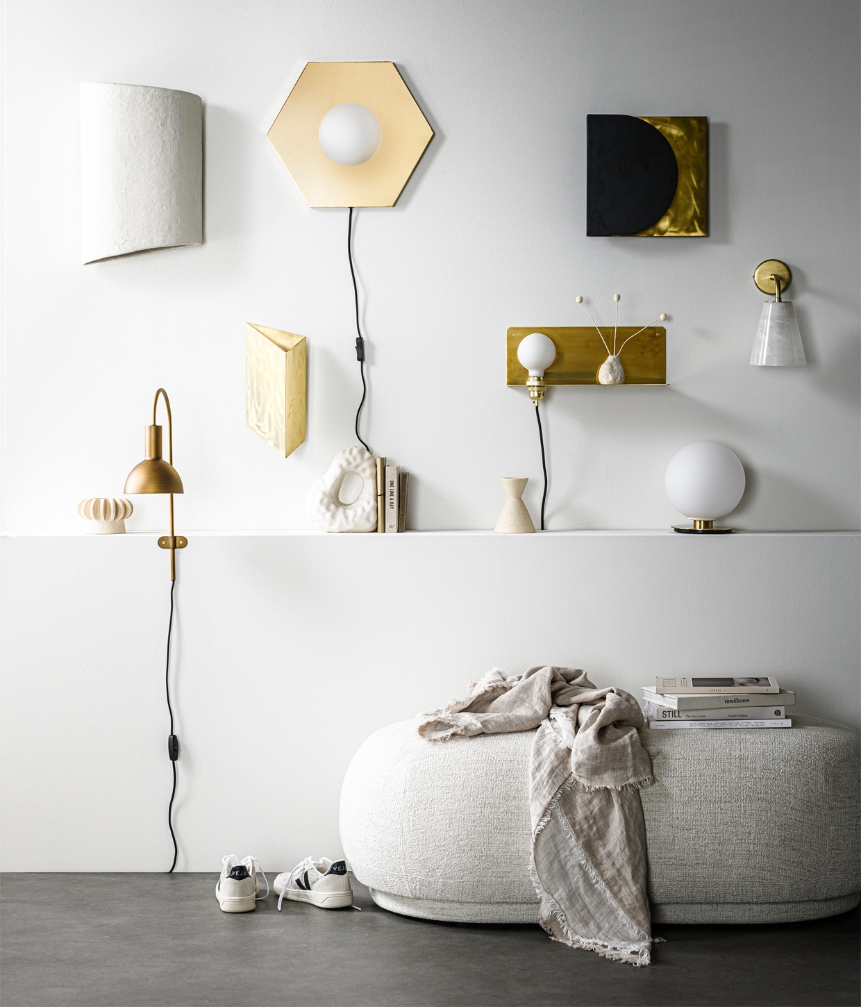 wandlamp White Earth van papier-maché, 45x31x16 cm (hxlxb) € 209,- (serax.com). Zeshoekige wand- of plafondlamp Holo, messing coating en opaalglas, 42×36,5×8,5 cm (bxhxd) € 299,- (festamsterdam.com). Wandlamp in zwart en messing € 249,-, driehoekige messing wandlamp van ontwerper Koen van Guijze € 390,- (serax.com). Messing wandplank met verlichting van Frama, 15x40x15 cm € 325,- (wonenmetlef.nl). Wandlamp met albasten kap en goudkleurige metalen voet, 18,5×26,5×14 cm € 169,- (zarahome.com). Messing wandlamp Oscar, 36x14x25 cm (lxbxh) € 49,95 (karwei.nl). Bollamp van opaalglas op geborstelde messing voet uit TR collection van Menu € 259,40 (vtwonen.nl). Kleine wit geglazuurde stenen vaas Vulca van Ferm Living € 15,- (wonenmetlef.nl). Ovale poef Rico Ottoman van , Ferm Living, 41x124x69 cm (hxbxd) € 1219,-, porseleinen boekensteun Boulder van Hay € 75,- (vtwonen.nl). Linnen plaid,140×190 cm € 79,99 (zarahome.com). Gympen van Veja € 125,- (bellerose.be). Vazen met losse onderdelen, om te stapelen of los van elkaar neer te zetten, per onderdeel van € 30,- tot € 57,50 (studio-yen.com). Overig privébezit. vtwonen 13-2020 | Styling Kim van Rossenberg | Fotografie Sjoerd Eickmans