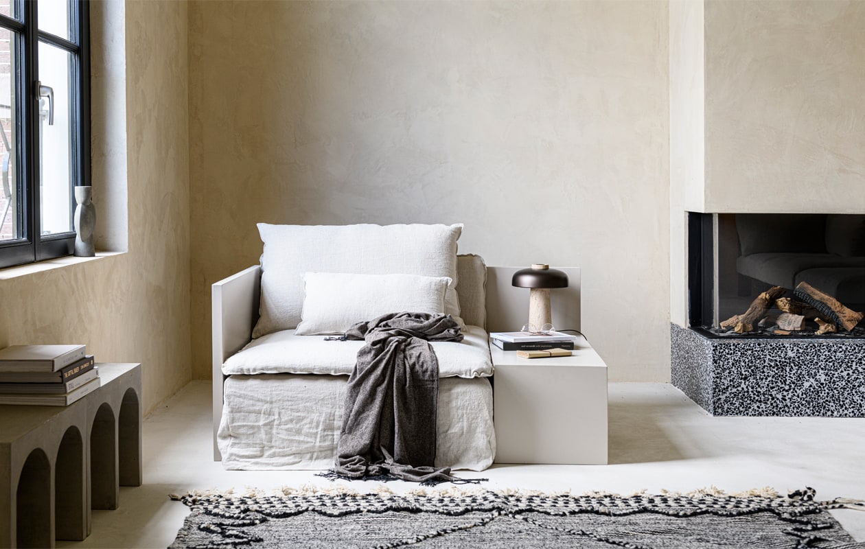 Kleur van het meubel Rolling Fog 143 (littlegreene.nl). 1-zitselement Söderhamn Samsta, 93x99x83 cm (bxdxh) € 199,- (ikea.nl). Losse hoes in ongebleekt linnen Rosendal € 399,- (bemz.com). Betonnen bank, 61x24x40 cm (bxlxh) € 195,-, Marokkaans vloerkleed, 200×300 cm € 900,-, kleur op de wand boven Mikonos, daaronder 100% natuurlijke clay stuc in de kleur Ibiza, op de vloer Urban Clay in de kleur Mikonos van We Are Wow Makers, prijs op aanvraag (anoukb.com). Plaid, 140×190 cm € 35,99 (zarahome.com). Tafellamp Reverse van Menu € 549,95 (designtales.nl). Geribbeld glas € 1,95 (loods5.nl). Overig privébezit.