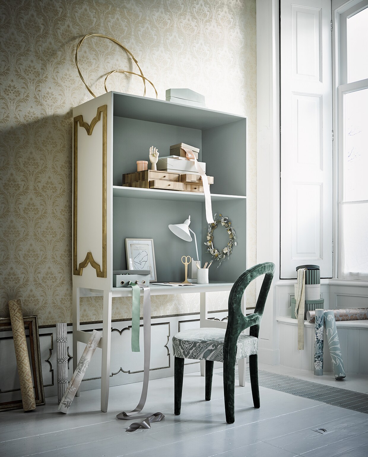 Behang aan de bovenzijde van de wand, Trianon Vol. II388531 (eijffinger.com). Lambrisering: behang MRV-25 Wainscoting van Mr. &amp; Mrs. Vintage in de kleur White, 48,7×487 cm (nlxl.eu). Alle behangsoorten van Designers Guild en Osborne &amp; Little in de vensterbank en op de grond , behang van Nina Campbell, per meter € 74,80 (wva.nl). Bekleding van de stoelzitting van Nobilis (wva.nl). Secretaire (com-anders.nl). Verf aan de buitenkant van de kast in de kleur Dimity van Farrow &amp; Ball; binnenkant Blue Gray van Farrow &amp; Ball (deruamsterdam.nl). Groene fluwelen stoel (covanderhorst.nl). Siervorm op kast van HKliving € 69,95 (deens.nl). Houten hand in de kast, roze glazen potje, kartonnen doos op houten box, schaar, plakband-apparaat, potloden, gouden pen (hay-amsterdam.com). Houten ladekastje (homestede.nl). Groene doos met vier nestels, ronde dozen in drie maten (sostrenegrene.com). Witte lamp (loods5.nl). Kunstwerk (tinystories.nl). Bloemenkrans (maisonnl.com). Overig privébezit.