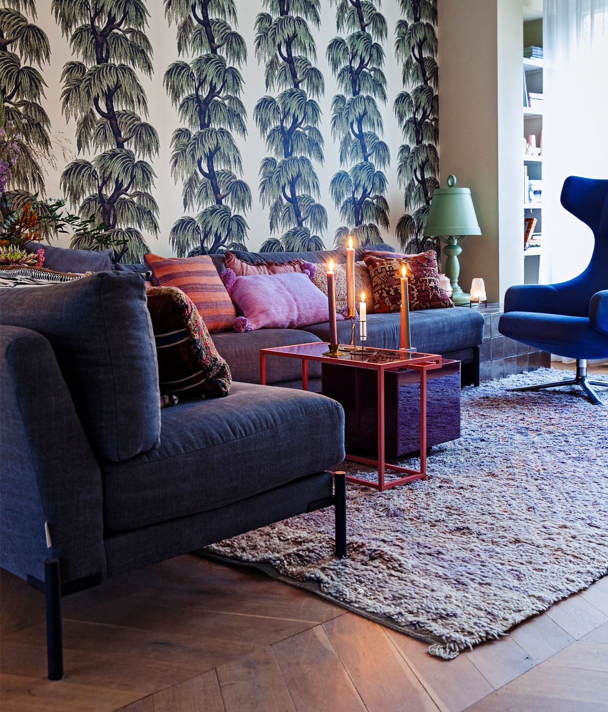 Behang Babylon van House of Hackney, vloer eikenhouten Hongaarse punt via De Oude Plank, vloerkleed Beni M’guild van World of Blends, bank Sleeve 3-zits en Sleeve loveseat vtwonen, fauteuil Grand Repos Vitra, bijzettafel roze prototype van Ontwerpduo gekocht tijdens Dutch Design Week, bijzettafel paars Mirror Block Table HKliving, kaarsen Sissy-Boy, kandelaars Household Hardware en Sissy-Boy, groene tafellamp Paper Moooi, kleine lamp waxine oudelampentafellichtje Piet Hein Eek, kussens vintage berber The Souks. vtwonen 12-2020 | Styling Ilona Jongepier | Fotografie Dana van Leeuwen | Tekst Anna van der Heijden