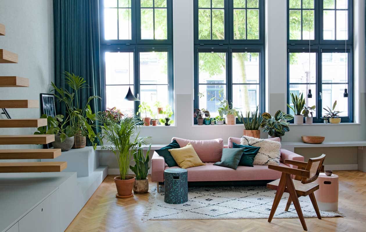 Behang Bazar 219427 van BN Walls. Zwevende eikenhouten trap Decotrap, behandeld met houtolie Monocoat Mist 5%. Ingelijste poster Junique. Vensterbank en kasten op maat gemaakt door Fontijn Interieur Projecten. Hanglampen Malou van Karwei (links) en Mora van Zuiver.Zit-slaapbank Innovation, kussens Karwei en Innovation, wit kussen souvenir uit Marokko. Aardewerken tuinkrukken gebruikt als bijzettafels Made. Stoel Pierre JeanneretOffice Chair via Object Embassy. Kleed Karwei. Planten De Balkonie en Sprinklr, terracotta bloempotten onder andere Sprinklr, Søstrene Grene en H&amp;M Home. vtwonen special binnenkijken 12-2020 | styling Geertje Planken | fotografie Caroline Coehorst