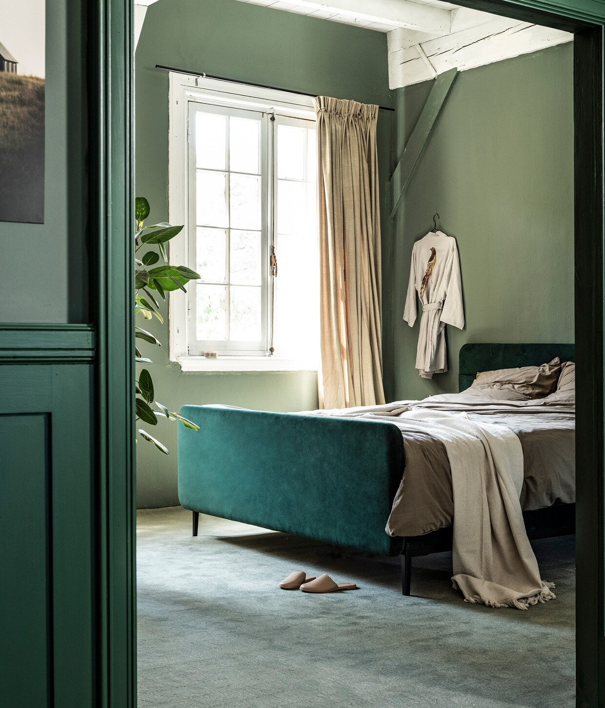Boxspring Basil in stof Glory kleur Bottle Green, met voetbord, 180×120 cm vanaf € 2450,-. M.m.v. vtwonen.nl (beddengoed van vtwonen, tapijt Padded Moss van vtwonen), karwei.nl (muurverf Army Green van vtwonen, op deur lakverf Moss van vtwonen), ikea.nl (plaid), hammam34.com (badjas), hm.com (leren slippers). Overig privébezit.
