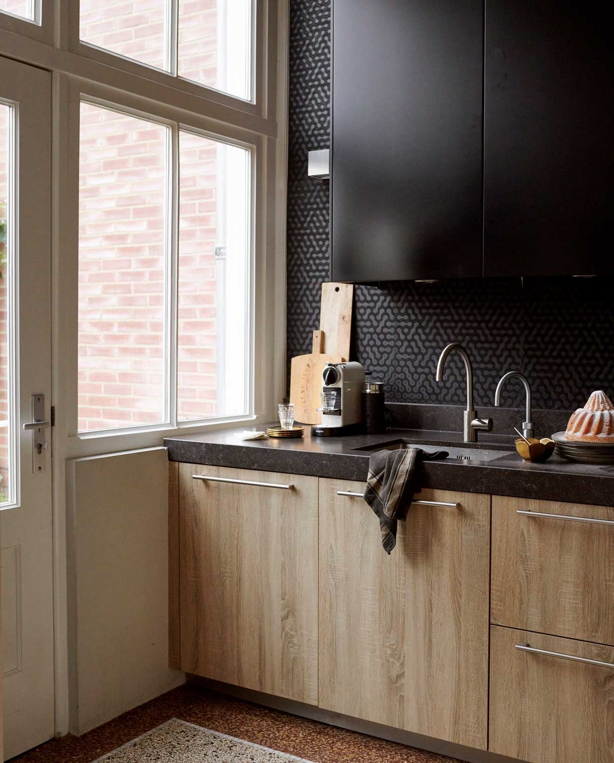 De granieten vloer is ambachtelijk gemaakt door Sminia Terrazzo, muurtegels zijn originele elementen in het huis, keuken en keukenkastjes Cook Devies Haarlem – merk onbekend, mand Loods 5, hanglamp Copper Tom Dixon, vaas van het tuincentrum, broodplanken gekregen.