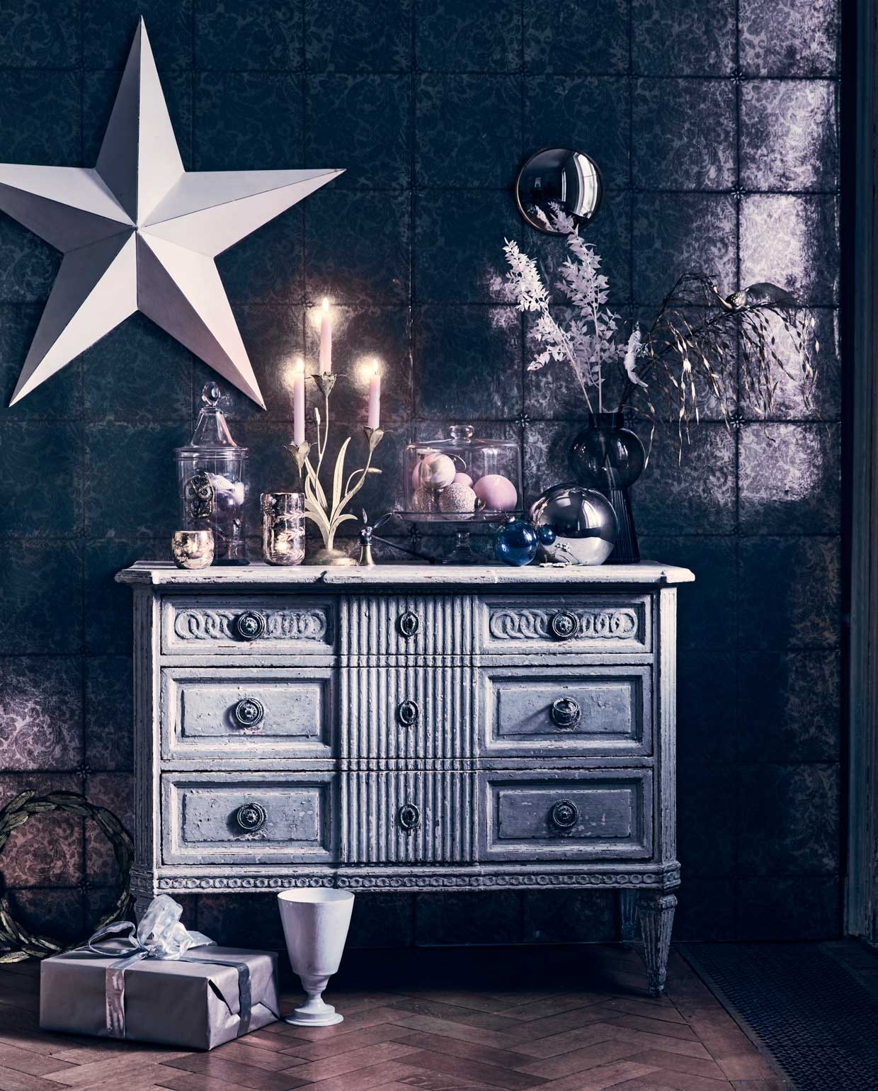 Behang Kings Mirror 98/13055 van Cole &amp; Son, rol 50 cmx10 m € 128,- (deruamsterdam.nl). Antiek dressoir, prijs op aanvraag., glazen stolp met taartplateau € 295,-, voorraadpot met puntdeksel € 350,- (pietjonker.nl). Witte ster € 95,-, grote zilverkleurige waxinelichthouder € 19,50, kleine waxinelichthouder € 8,95, kleine ronde spiegel € 19,50 (weldaad.com). Kaarsendover € 39,95, witte vaas van Astier € 195,- (maisonnl.com). Roze glitterkerstballen € 4,50, gemarmerde roze kerstballen € 4,50 (nordal.eu), grijze glazen vaas van Bloomingville € 43,50 (vtwonen.nl). Zilveren glazen bal € 19,99 (hm.com). Grote transparante blauwe bal € 9,95, kleine kerstballen in voorraadpot vanaf € 1,95 (iblaursen.nl). Gouden krans van blaadjes € 51,99, gouden kandelaar € 30,- (bungalow.dk). Vogeldecoratie op tak € 14,99 (sissy-boy.com). Overig privébezit.