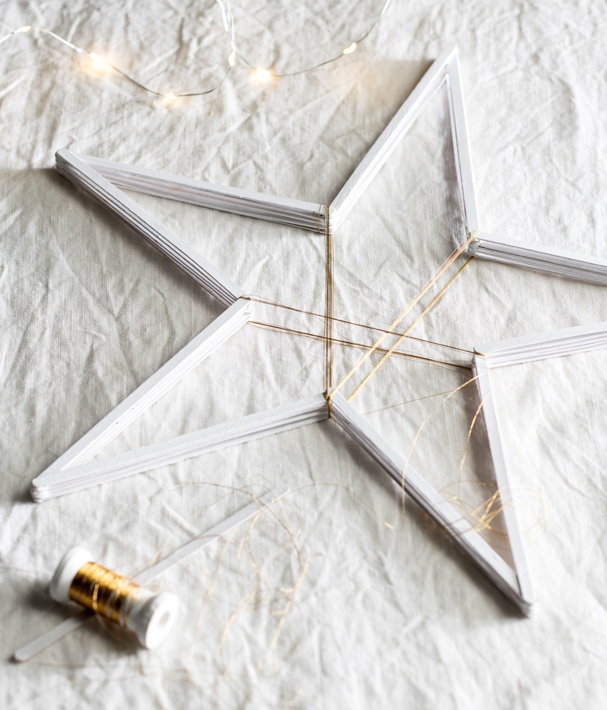 IJsstokjes 19×0,6 cm € 6,50 (creaknutselen.nl). Goudkleurig borduurgaren € 2,75 (hema.nl). Verf wit zijdeglans € 6,99, lichtsnoer led € 2,49 (action.nl). Linnen tafelkleed € 39,99 (hm.com). styling Mila Griese | fotografie Louis Lemaire