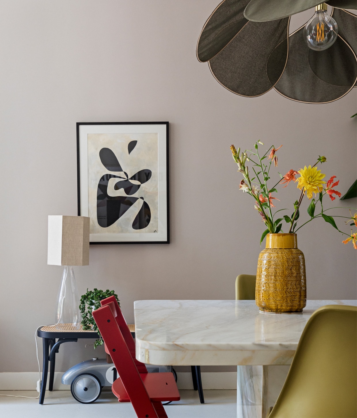 Kunstwerk Cate Adriana, glazen tafellamp en eetkamerstoelen Casa Gitane met kap van HKliving, rotan bankje Westwing, speelgoedauto gekregen, rode kinderstoel Stokke, tafel Marktplaats, gele vaas Leen Bakker, groene lamp Rockett St George. vtwonen 11-2020 | Productie en styling Ilona Jongepier | Fotografie Dana van Leeuwen | Tekst Anna van der Heijden