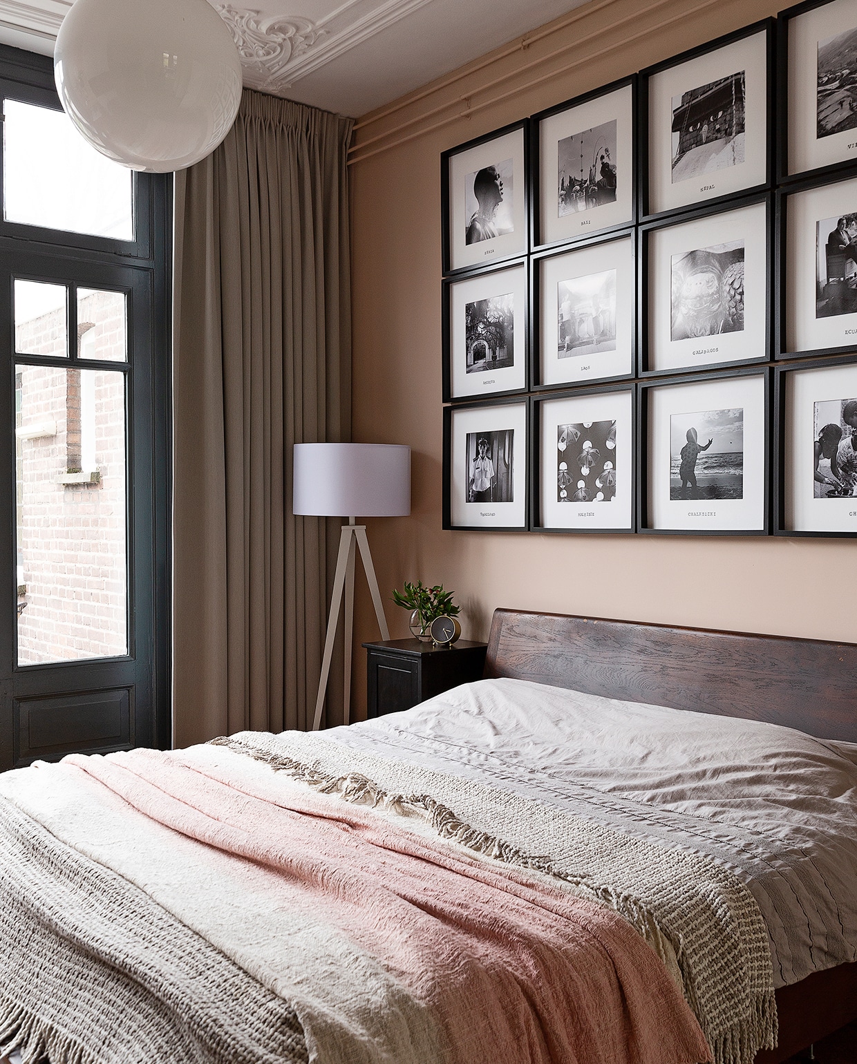 Op de wand boven het bed foto’s van alle verre reizen die Merijn en Stan hebben gemaakt. Lijsten Ikea. Bed Goossens. Vloerlamp Zuiver. Roze sprei Loods 5. De beige sprei kochten ze tijdens hun huwelijksreis in Ecuador. vtwonen 04-2020 | styling Emmy van Dantzig | fotografie Jansje Klazinga | tekst Anne van den Dool