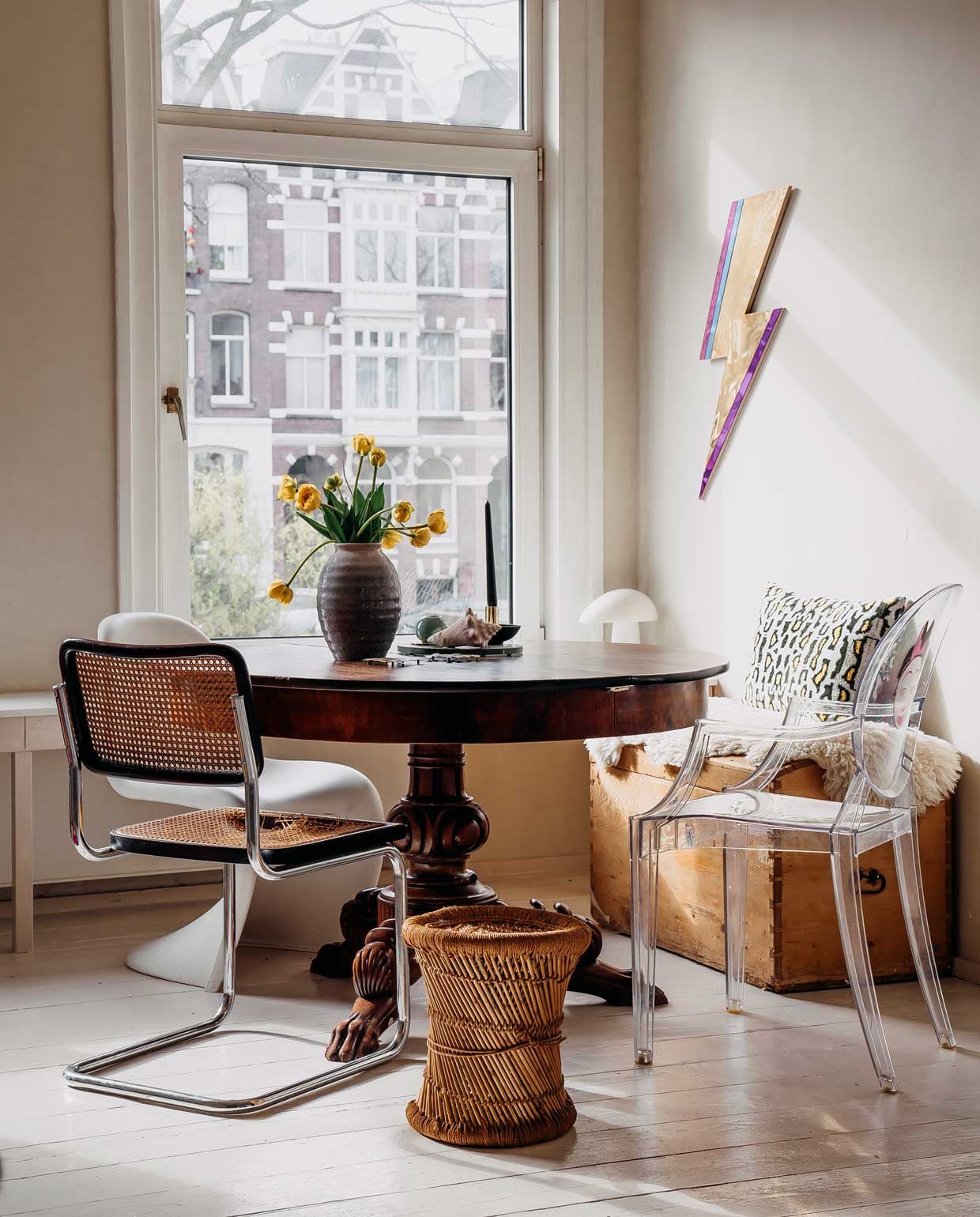 Tafel, kist en vaas, erfstukken. Tafellamp Night Owl van Lightyears. Krukje Marktplaats. Witte stoel Verner Panton van Vitra, transparante stoel Louis Ghost van Kartell, zwarte stoel vintage. Foto aan de wand uit de serie ‘Paula’ van Hendrik Kerstens. Bliksemschicht via Bride &amp; Wolfe. Vachtje gekocht op Noordermarkt. Kussen Living Stories.