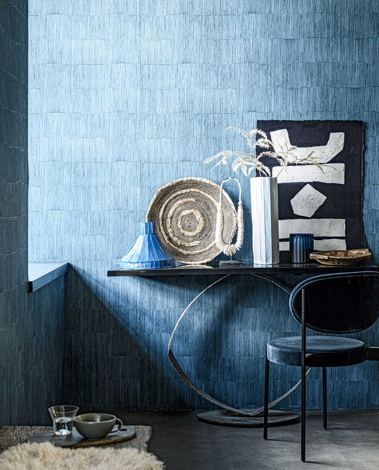 Behang Sakiori Ink uit de Casablanca-collectie van Designers Guild, rol 70 cm x 10 m € 117,- (wva.nl). Sidetable, 135x38x80 cm (lxdxh) prijs op aanvraag, geurkaars in blauw glas € 115,- (covanderhorst.nl). Oude geweven Makenge mand € 137,50 (couleurlocale.eu). Blauwe keramieken vaas € 232,50, witte keramieken vaas € 169,- (badenbaden.nl). Ketting op voet € 85,95, oude houten schaal € 27,50 (loods5.nl). Kunstwerk uit The Heritage Series, prijs op aanvraag (irisdorine.com). Stoel € 780,- (kasstoor.nl). Houten snijplank, per 2 € 79,- (fermliving.com). Glas van Serax, per 4 € 32,99 (vtwonen.nl). Mok € 9,- (paviljoennoord.com). Schapenvacht € 99,- (studio-yen.com). styling Danielle Verheul | fotografie Sjoerd Eickmans