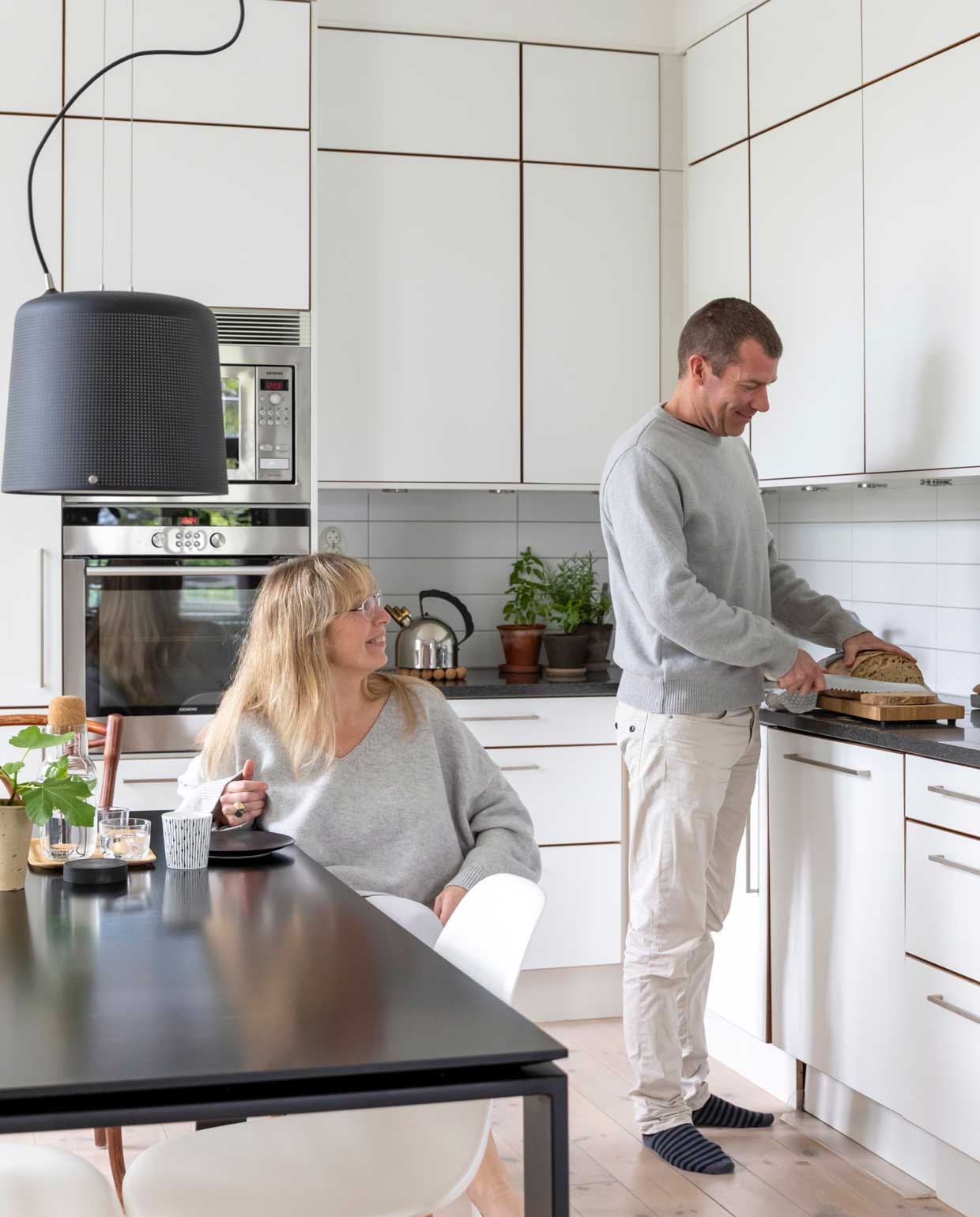 De keuken zat al in het appartement toen ze er kwamen wonen. Camilla: ‘Ik had zelf niet voor zo’n aanrecht van zwart graniet gekozen, omdat het zo hard is. Aan de andere kant is het wel praktisch, en het is ruim genoeg om met z’n vieren te koken. In de hoge kasten kun je veel kwijt en ze ogen rustiger dan kleintjes. De deuren hebben randen van donker eikenhout.’ Keukenkasten Marbodal. Eettafel Kartell, stoelen Eames, hanglamp Vipp.