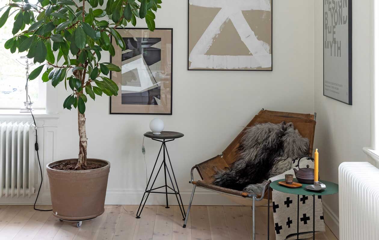 Fauteuil J361 van Erik Ole Jørgensen, plaid Serax, kruk Sisman, tafellamp Flos, bijzettafel en kandelaar Zeta, poster rechts is gekocht bij het Röhsska Museum, de twee kunstwerken zijn van Camilla.
