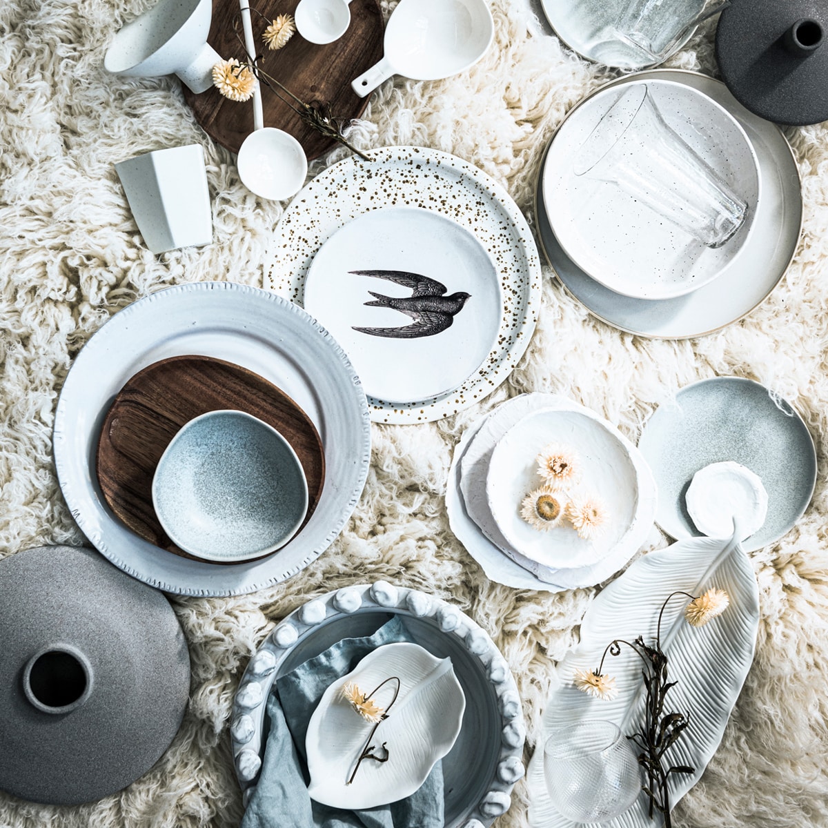 Houten borden, bruin gevlekt bord, zachtblauwe kommen, zachtblauwe borden, blauw linnen servet (hm.com). Witte keramieken lepels, XL wit bord met bewerkte rand, schaal met bollen, blad schaal klein, blad schaal groot (stadspaviljoennoord.nl). Porseleinen bord met vogel (maisonnl.com). Kom op poot, geometrische beker (hkliving.nl). Glazen met uitlopende bovenkant van Serax, zachtgrijs bord met bruine rand van Serax (vtwonen.nl). Diep bord met vlekjes (loods5.nl). Kleine grijze vaas, grote grijze vaas, wijnglas (bolia.com). Papier-maché borden (nrdrhvn91.nl). Wollen vloerkleed, 200×300 cm (lxb) (therealrugcompany.co.uk). Overig privébezit.
