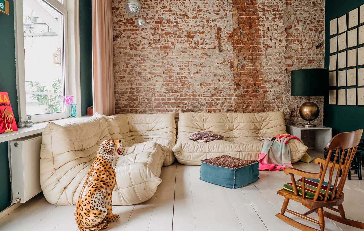 Bank Togo van Ligne Roset, panter Dolores Del Dia. Poef bekleed door stoffeerderij Aan het Park. Schommelstoel erfstuk. Home-lamp cadeau gekregen. Kleur plafond en vloer Cool Concrete, het donkergroen is Quite Clearing, Histor. Gordijnen Marktplaats. Plaid Scholten &amp; Baijings. Discoballen Kitsch Kitchen. vtwonen 11-2020 | fotografie Muk van Lil