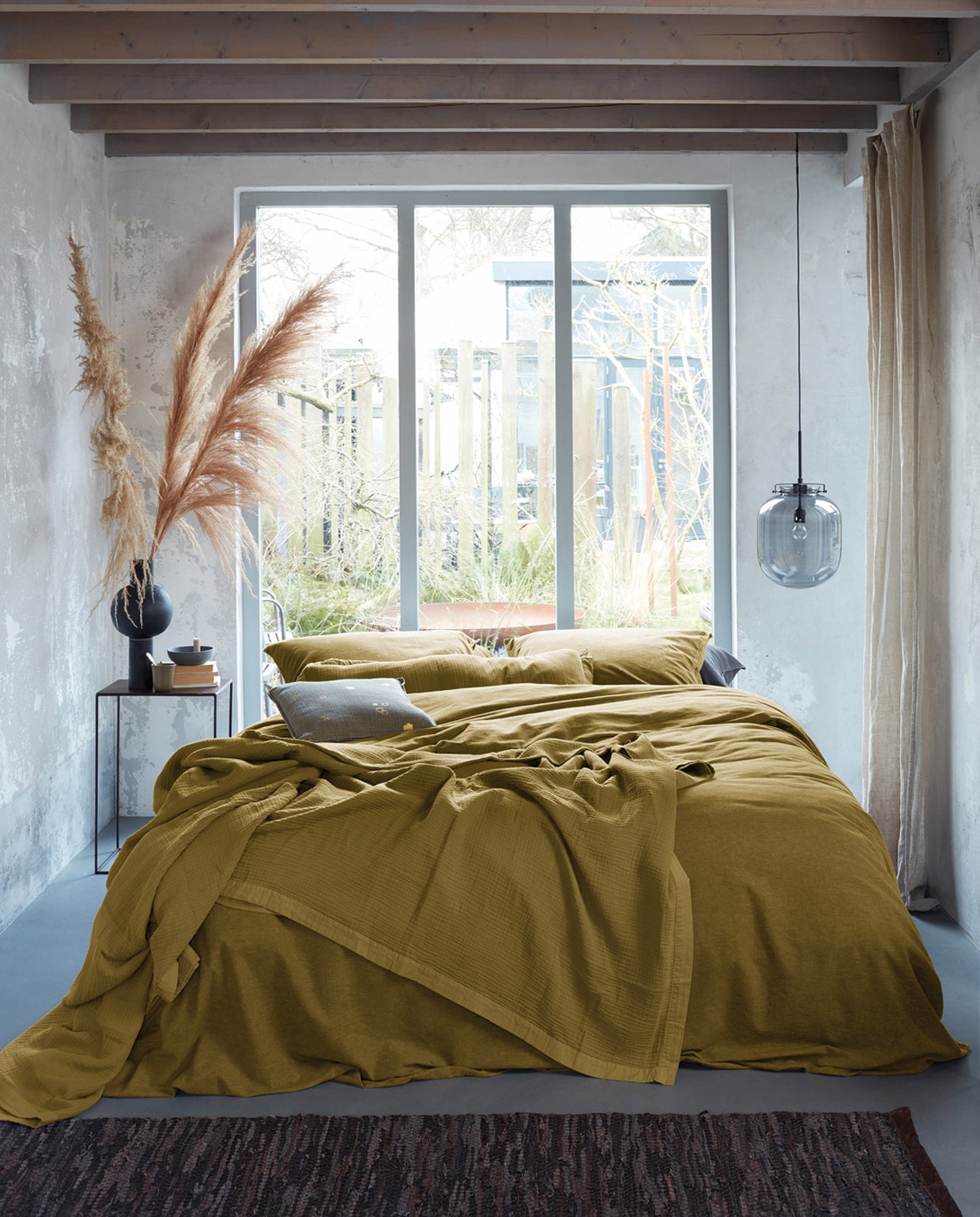Flanel in oker van 100% , katoenflanel, sprei Cuddle in oker , van 100% katoen, dot Square sand. Overige kussenslopen Flanel in grijs. M.m.v. thingsilikethingilove.com (bijzettafels), loods5.nl (zwarte vaas, kandelaar, dienblad), letoile.store (mok, karaf, hoornen schaal), loods5.nl/design (vloerkleed), vtwonen.nl (hanglamp).