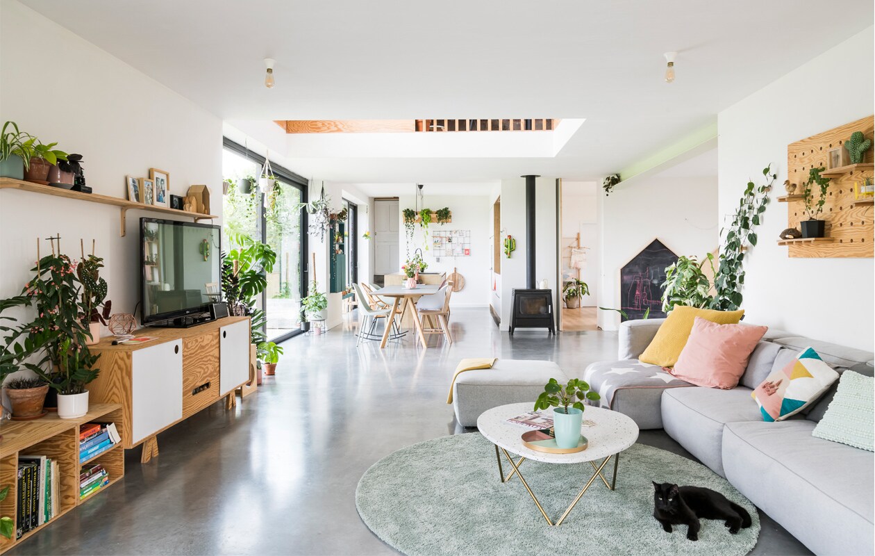 De stallen maakten plaats voor een ruime en lichte woonkamer met open keuken. Pegboard en schoolbord zelfgemaakt. Bank Mags Soft van Hay. Kussens Zodio, Action en Hay. Vloerkleed Ikea, salontafel Furnified. Houtkachel Aduro.