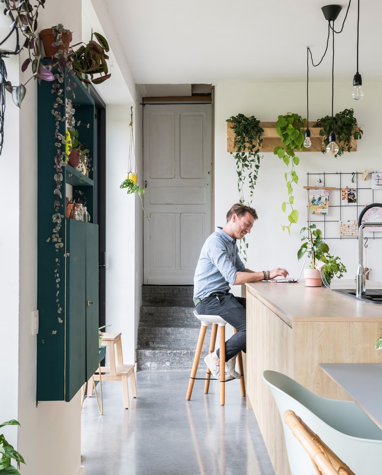 Vroeger zat achter deze deur een badkamer, die is verhuisd naar de eerste verdieping. Omdat ze hier en daar wel een verwijzing naar de geschiedenis van de hoeve wilden, lieten Femke en Nicolas de deur ongemoeid, net als de oude stenen trap. Barkruk Quinze &amp; Milan. Keuken Hans Keukens. Plantenrek zelfgemaakt. Groene kast van Nicolas’ grootvader. Kruk Ikea. Soortgelijk rek Xenos, S-haken vtwonen.