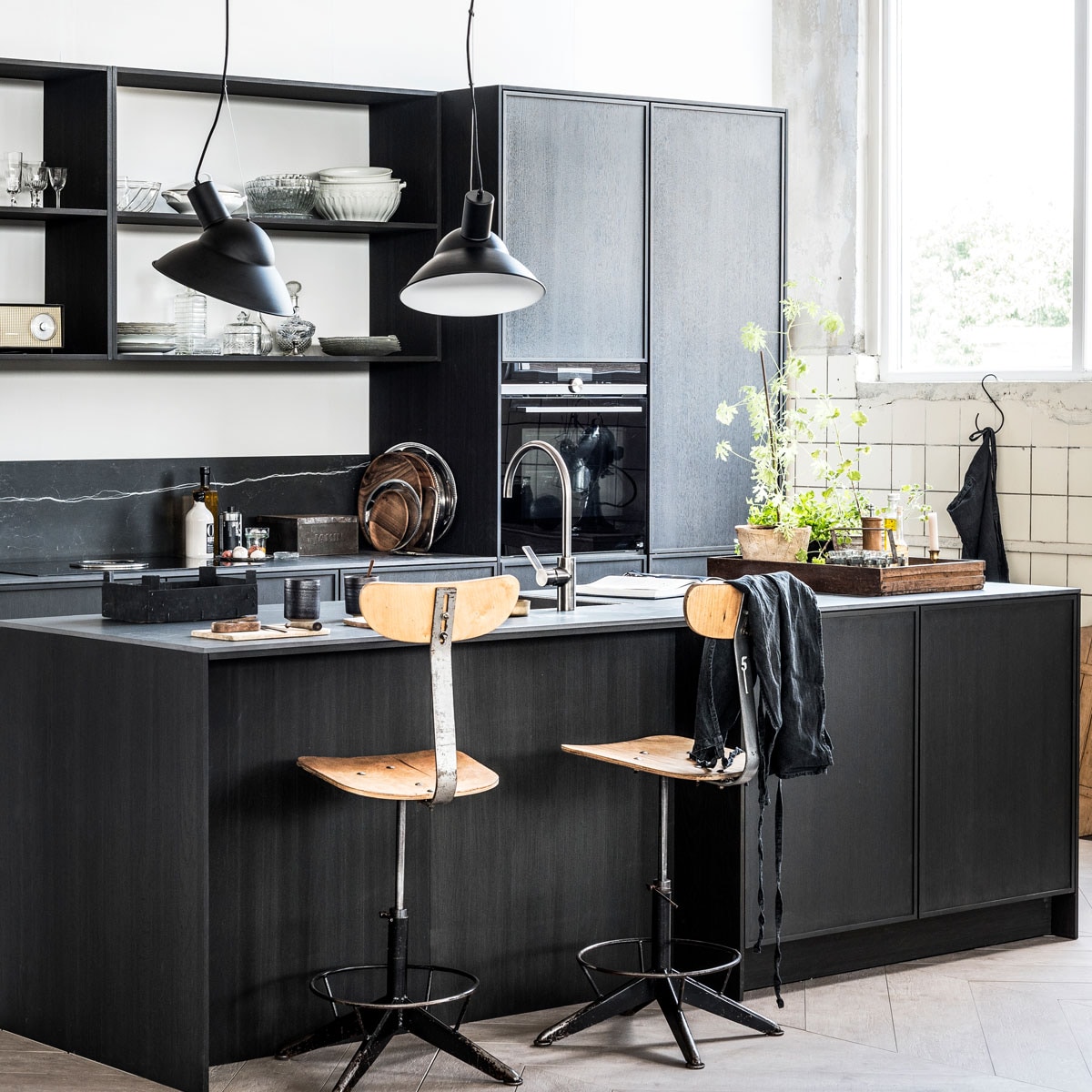 Zwart kookeiland met houten stoelen