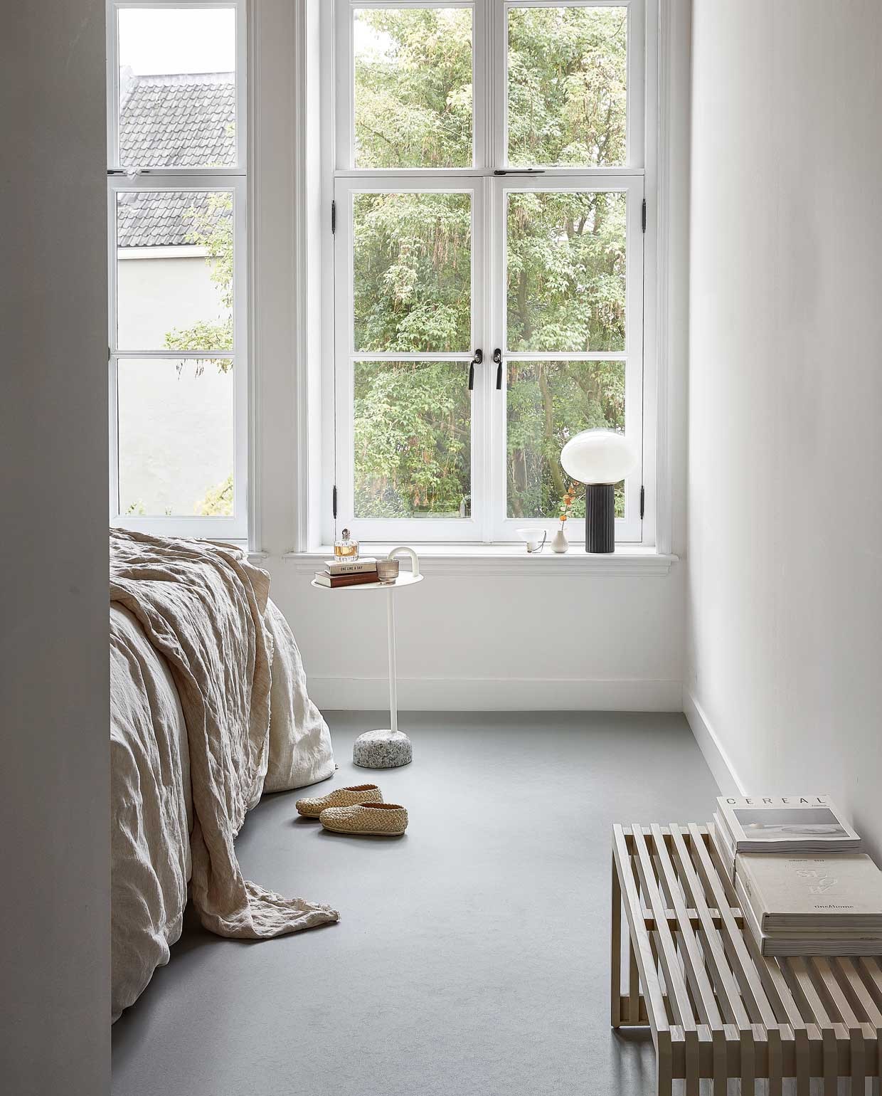 Marmoleum vloer kleur VTW08 Lood, per m² , € 43,95 (excl. installatie)., , M.m.v. nordal.eu (tafellamp met zwarte voet met opal glazen bol), hkliving.nl (zandkleurig lattenbankje, porseleinen kom op voet), vtwonen.nl (bijzettafel Bowler van Hay), zarahome.com (linnen dekbedovertrek, linnen plaid), suhka.nl (gevlochten slofjes), loods5.nl (beige geribbeld vaasje, grijs glas). Overig privébezit.