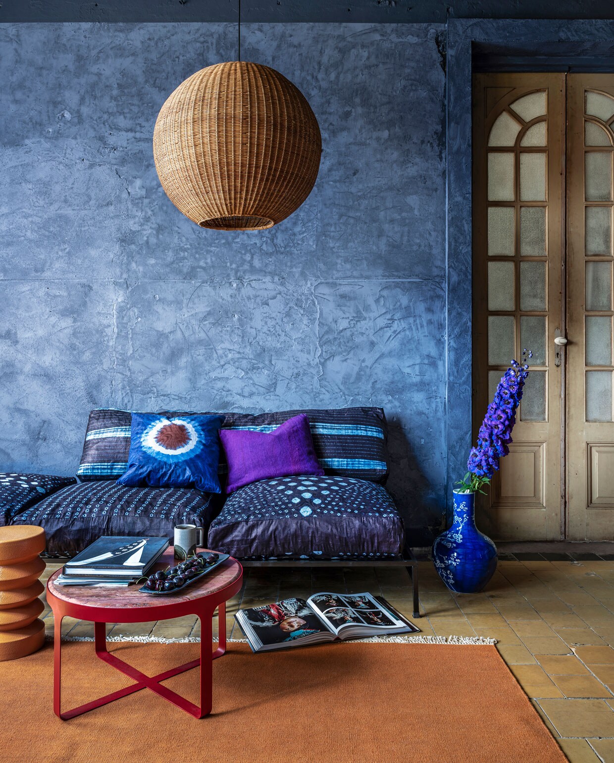 kleurrijke woonkamer met blauwe muur en oranje vloerkleed