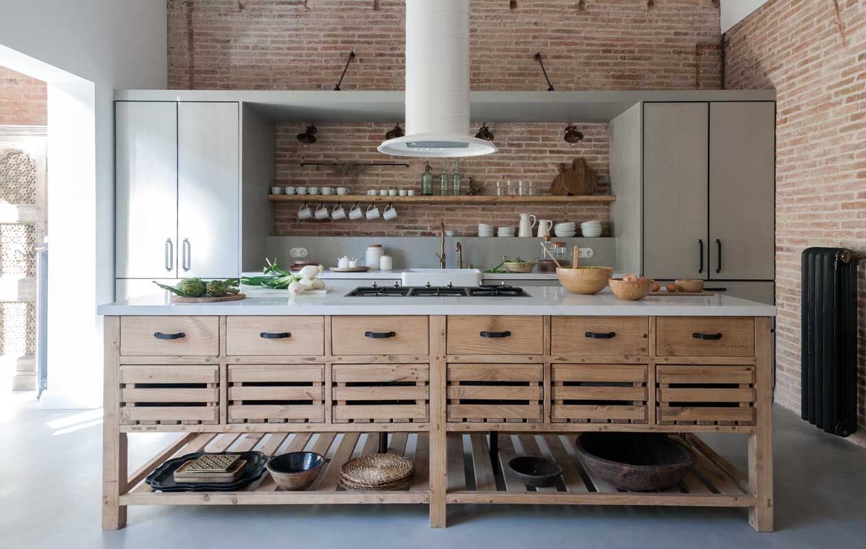 Frontjes van de keuken zijn van microcement, net als de vloer. Marmeren aanrecht van Compac, model Calacatta. Kraan Neve, gaskookplaat Smeg, de afzuigkap is eigen ontwerp en op maat gemaakt. Blikvangers zijn de ladekastjes, afkomstig uit het Indiase Rajasthan. Ambachtelijke houten schalen en wit porselein werden her en der verzameld. vtwonen 09-2020 | productie Vega Mg | fotografie Raül Candales | styling Susana Ocaña