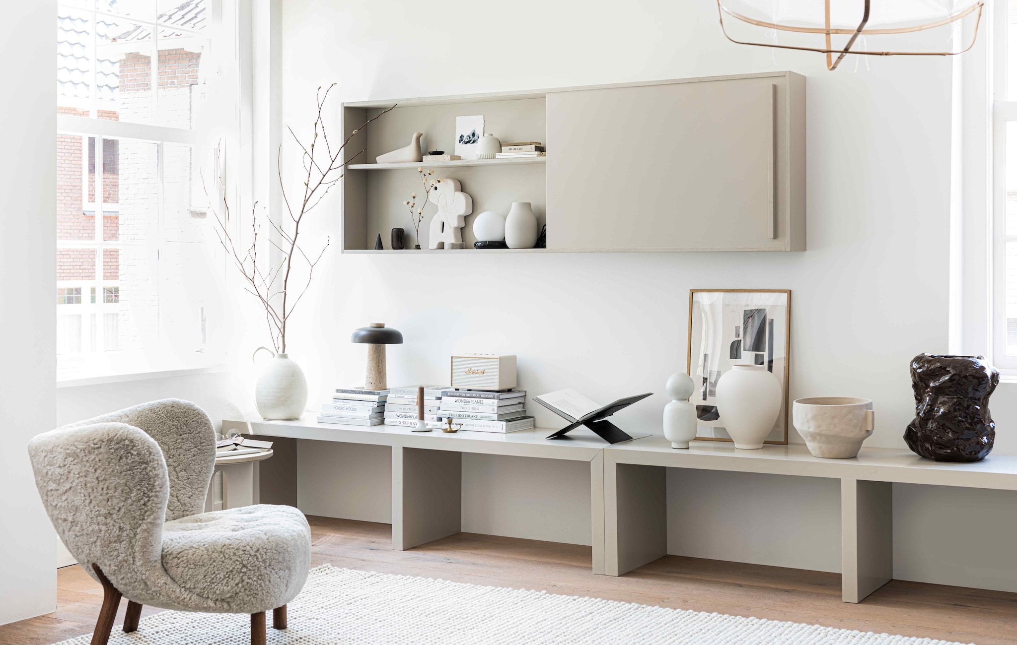 Fauteuil Little Petra van &amp;tradition € 2609,-, hanglamp van Ay illuminate € 429,- (flinders.nl). Vloerlamp JWDA met travertin voet € 1499,95, tafellamp met travertin voet en bronzen aluminium kap Reverse van Aleksandar Lazic € 550,- (menuspace.com). Vloerkleed Peas soft van Hay 300×200 cm € 935,-, witte vaas met boldop Muses Talia van Ferm Living € 79,- (vtwonen.nl). Vaas met oor en grote witte vaas vanaf € 45,99, aardewerken kom € 45,99 (zarahome.com). Zwarte stalen boekenstandaard € 45,- (mendo.nl). Poster Shapes, 140×50 cm € 47,75 (facade-apt.com). Eikenhouten frame A3-formaat € 54,95 (moebe.dk). Crèmekleurige wifi-luidspreker Marshall Acton € 274,- (coolblue.nl). Mok € 14,50 (suhka.nl). Verfkleur sidetable en tv-meubel Rolling Fog (littlegreen.nl). Sidetable op maat gemaakt, prijs op aanvraag (richardvanmeerveld.nl). In de kast: houten vogel L’Oiseau van Vitra € 108,-, wit ornament Chulucanas van HKliving € 39,-, beige vaas Colora van Blomus € 36,95, tafellamp zwarte ring met witte bollamp van Ferm Living € 199,- (vtwonen.nl). Overig privébezit. styling Kim van Rossenberg | fotografie Sjoerd Eickmans