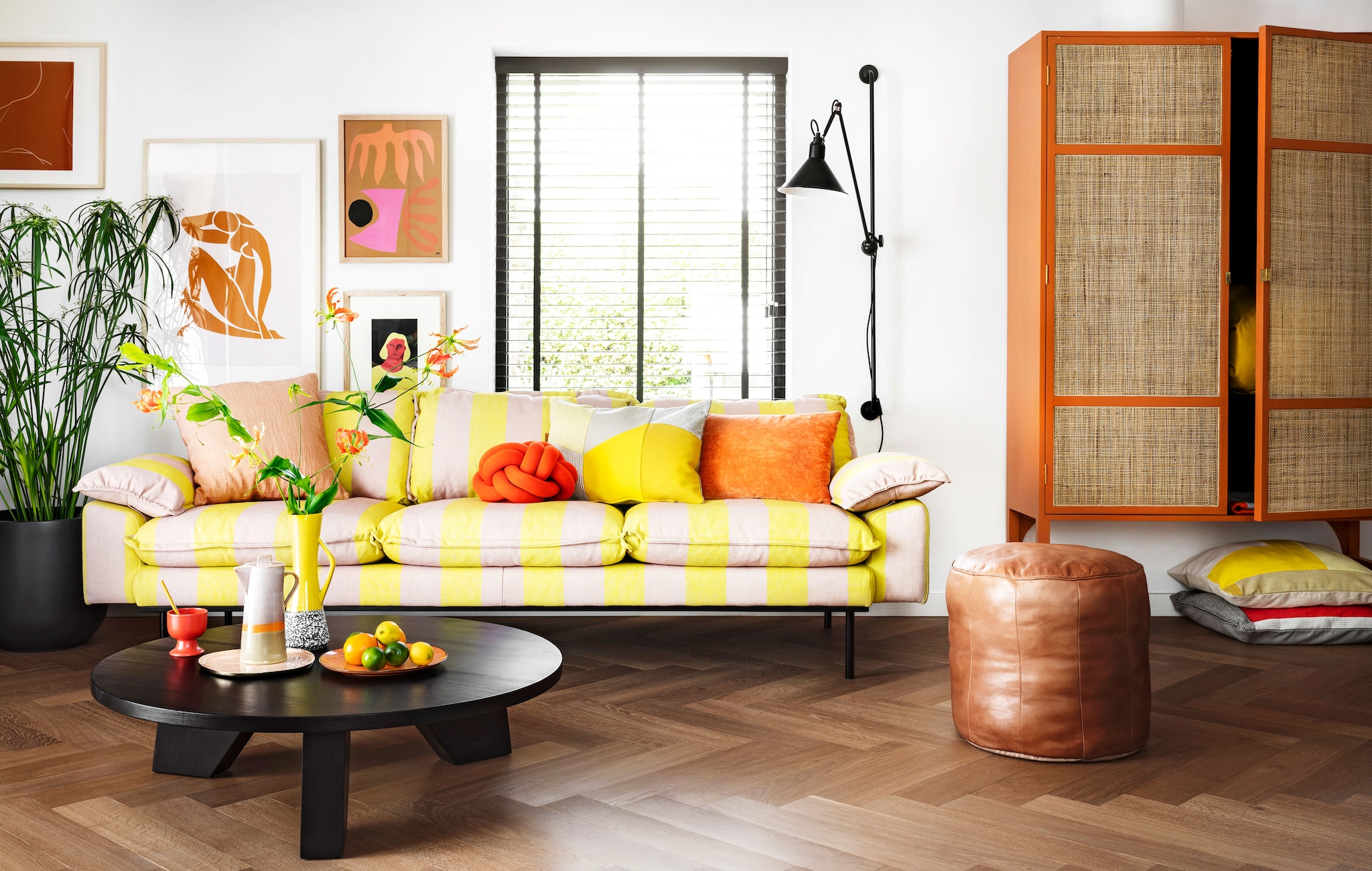 Driezitsbank Retro, 225x95x83 cm € 1925,-, oranje velvet kussen € 37,95, lijst,  rechtsboven Multi € 69,95, lijst daaronder Art Frame € 59,95, retro kast 125x40x200 cm,  (bxdxh) € 1495,-, koffiepot Seventies € 39,95, kopje op voet Kyoto € 3,75, dinerbord,  Peach € 19,95 (hkliving.nl). Kussen met grijze en gele vlakverdeling € 89,- (kus-sen.nl).,  Oudroze linnen kussen Empire € 45,-, leren poef Virginia € 159,95, salontafel Jay,  € 499,- (hetkabinet.nl). Sierkussen Knot van Design House Stockholm € 117,-, dienblad,  Imperfect van &amp;k Amsterdam (vtwonen.nl). Plantenpot Egg € 31,99 (praxis.nl). Plant,  Papyrus (Tuincentrum). Overig privébezit.