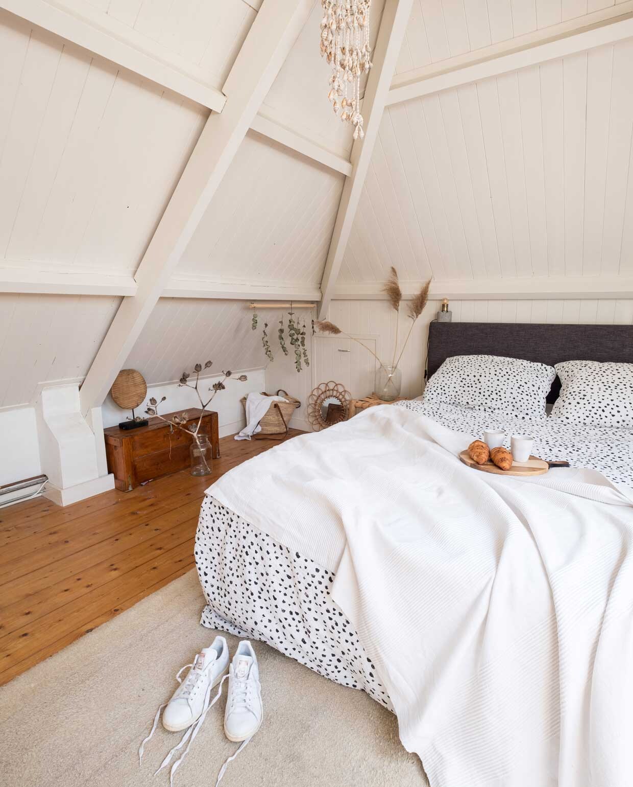 Bed Beter Bed, dekbedovertrek Crisp Sheets. Witte sprei, wollen kleed en schelpenhangersouvenir gekregen van familie. Leren krukken als nachtkasten Kwantum, nachtlampen Leen Bakker. Sneakers Adidas.