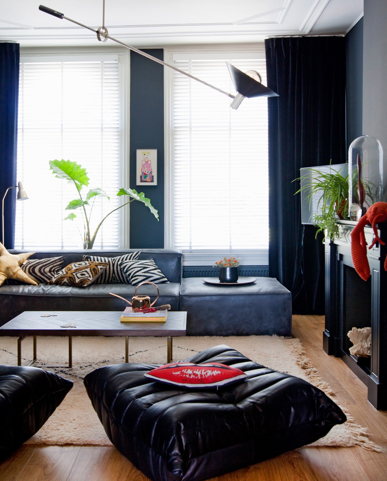 Poef en fauteuil van Ligne Roset. De hengellamp van Anvia, ontworpen door J.Hoogenvorst. Bank van Raw Materials (Amsterdam), kussens van Rough Studio’s, goudkleurige staande lamp van vtwonen.nl, koperen gieter van Wauw, plantenpot en stolp zijn vintage.